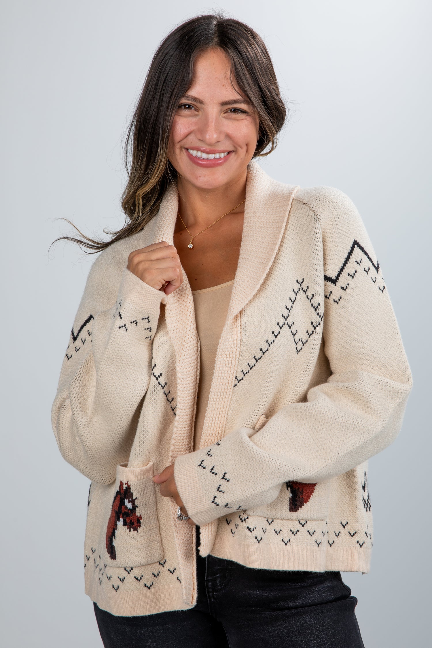 Woman wearing a cream-colored cardigan with patterned design on a plain background