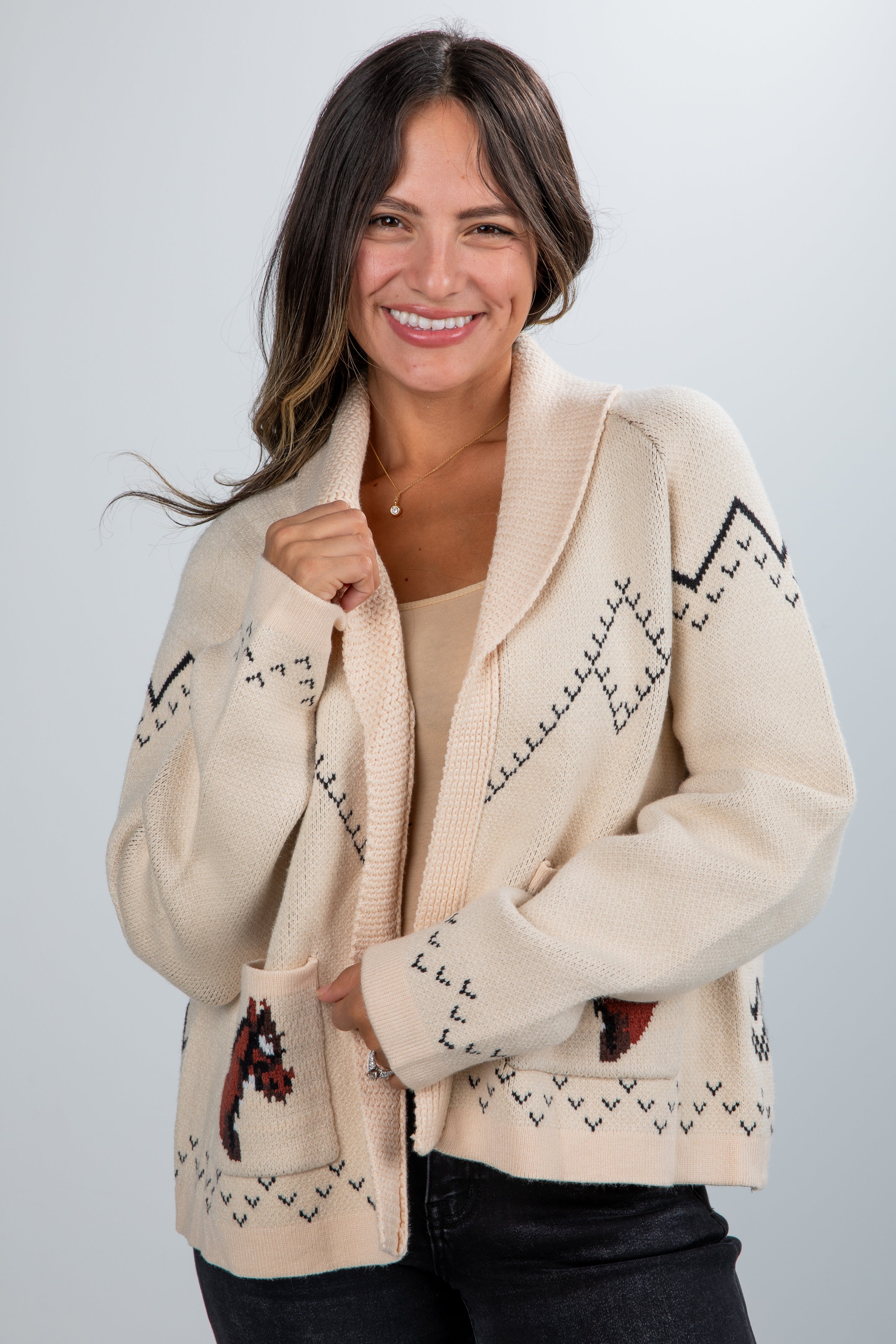 Woman wearing a cream-colored cardigan with patterned design on a plain background