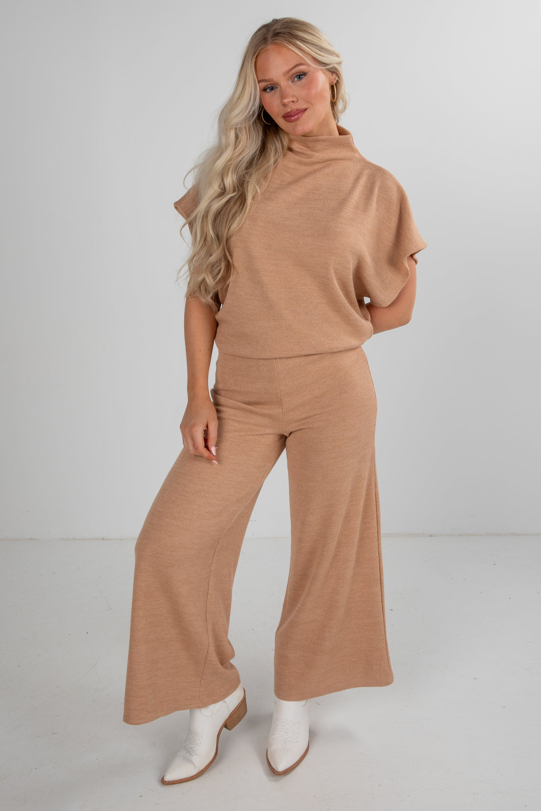 Woman wearing a beige outfit with wide-leg pants on a white background