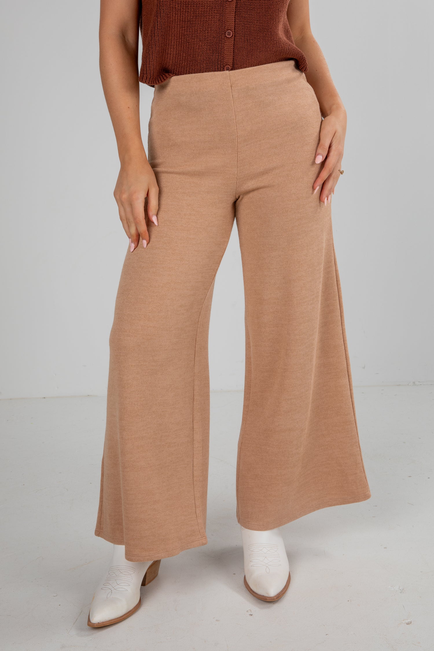Person wearing tan wide-leg pants on a plain background