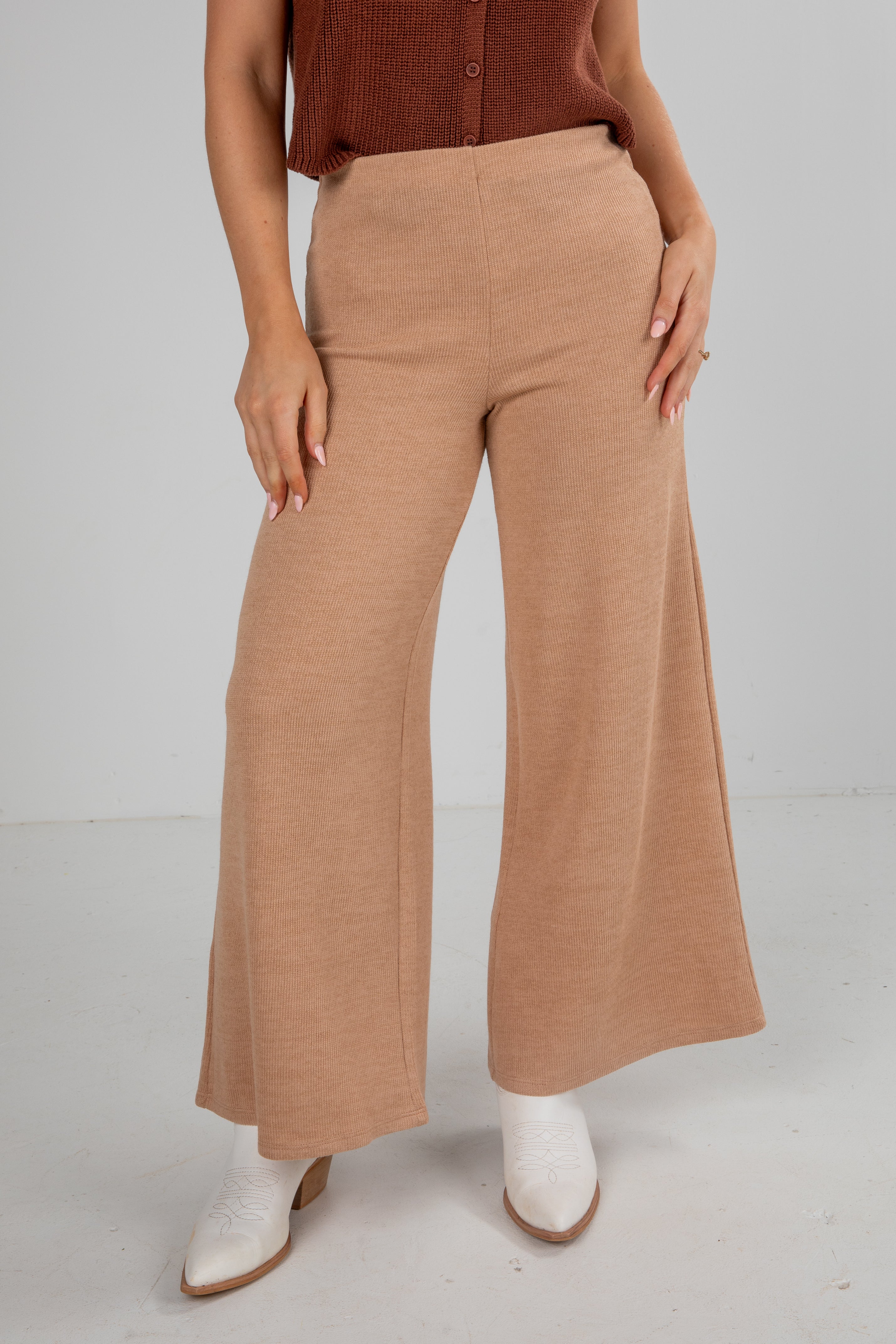 Person wearing tan wide-leg pants on a plain background