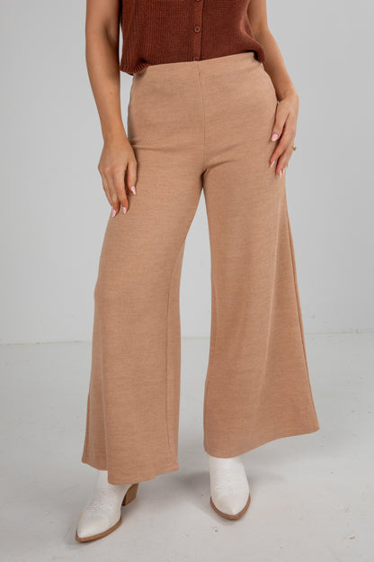 Person wearing tan wide-leg pants on a plain background