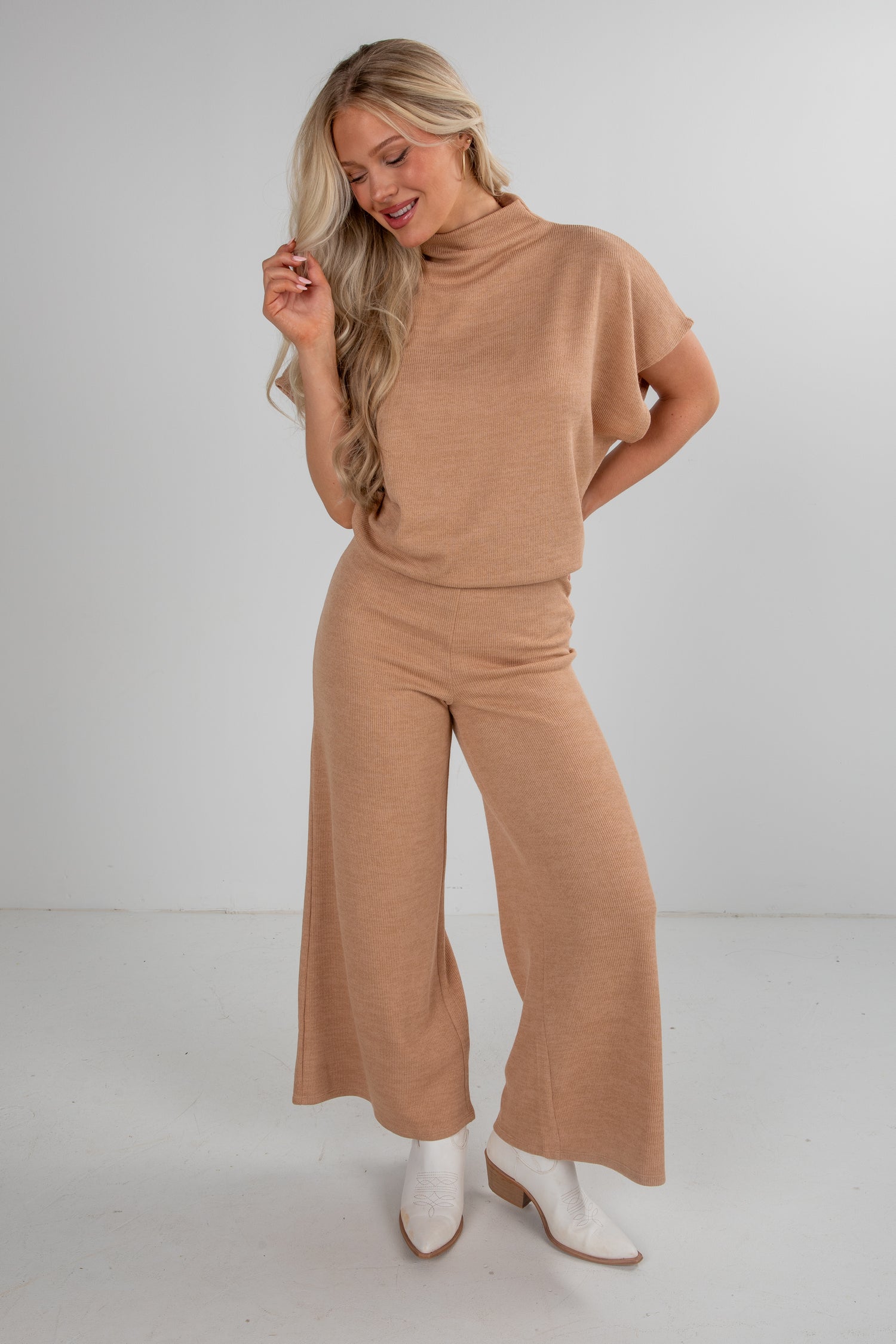 Woman wearing a beige outfit with wide-leg pants on a white background