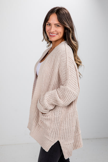 Woman wearing a beige knitted cardigan against a white background
