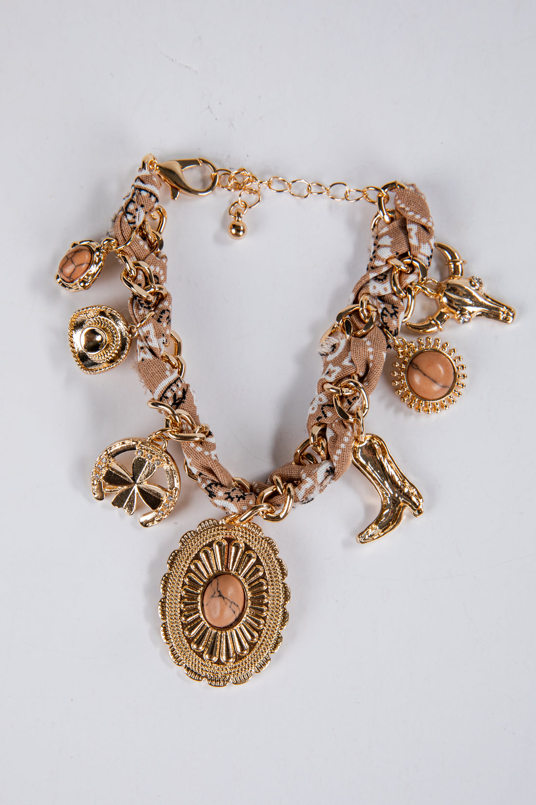Gold charm bracelet with various charms on a light gray background