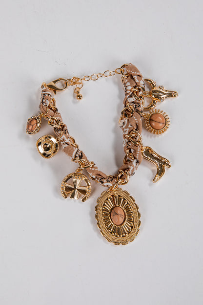 Gold charm bracelet with various charms on a light gray background