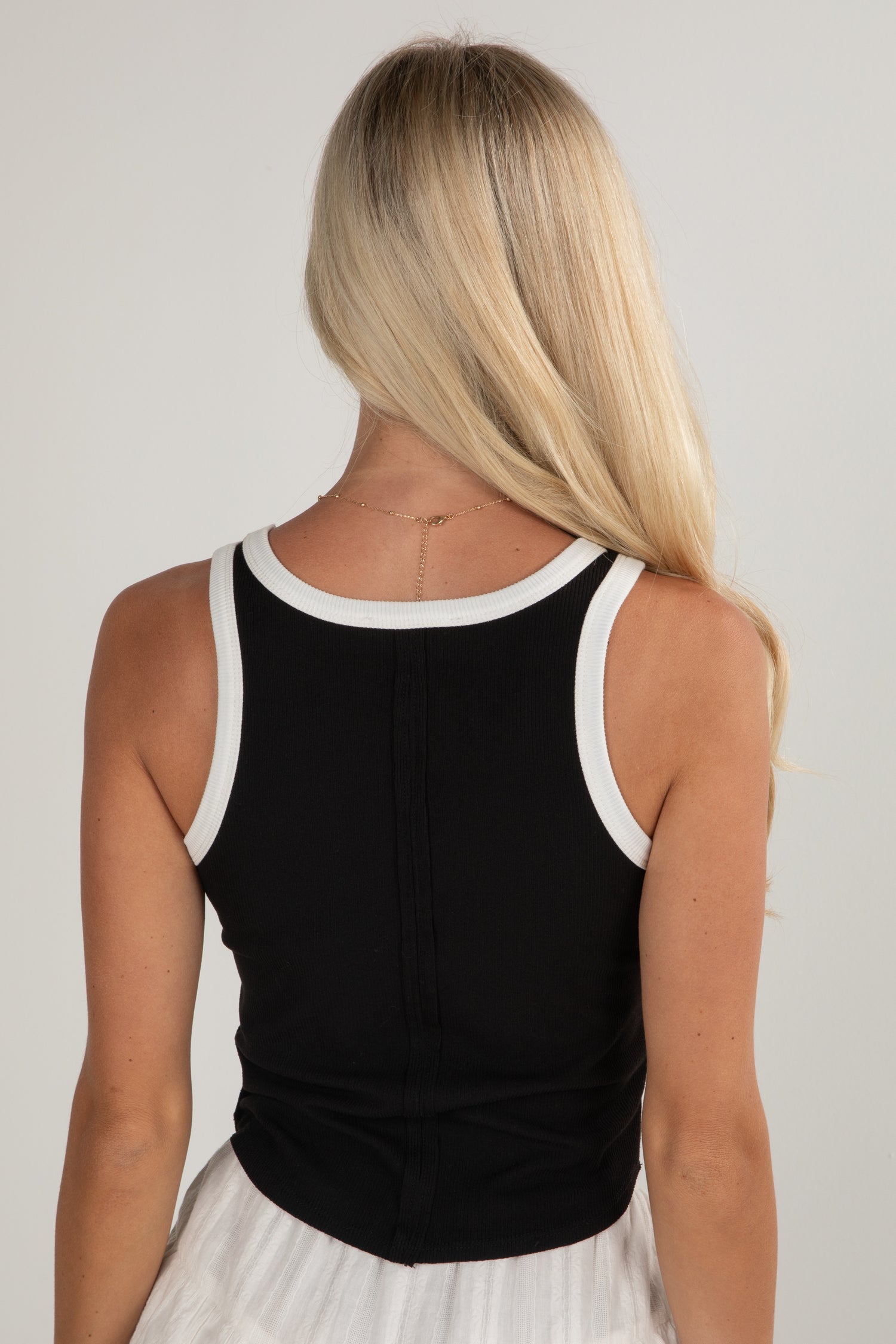 Person wearing a black tank top with white trim on a plain background