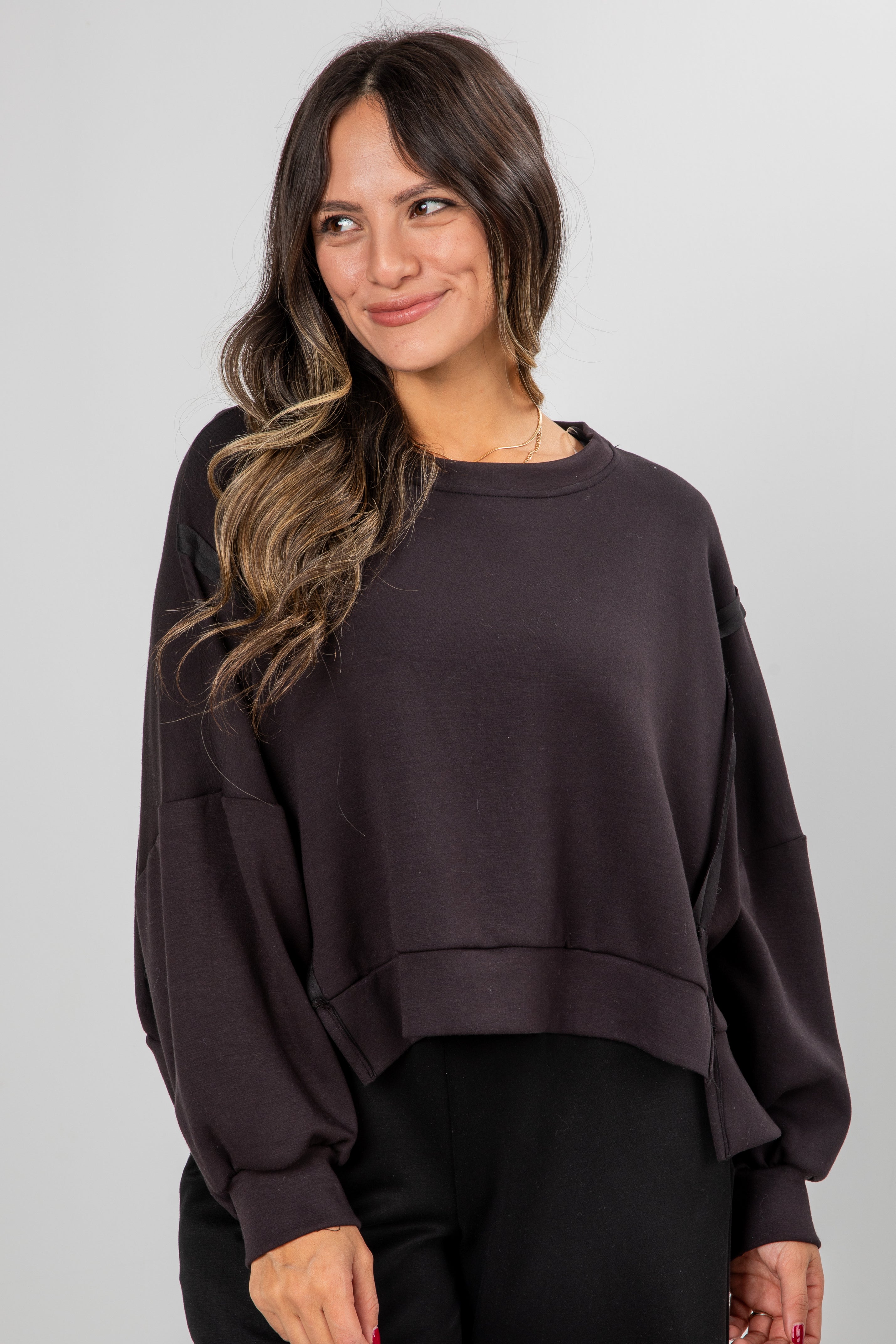 Woman wearing a dark brown oversized sweatshirt against a plain background