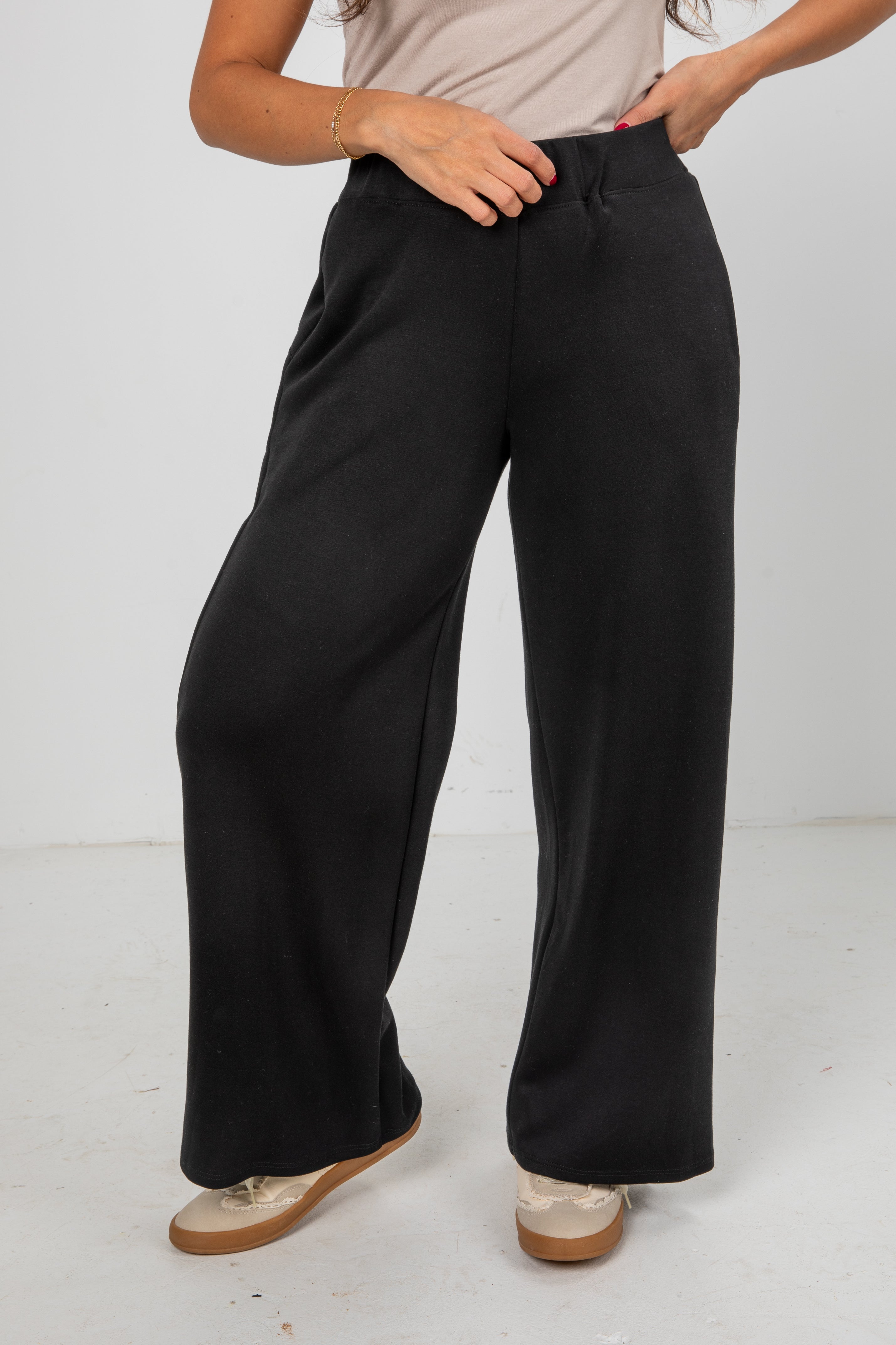 Person wearing black wide-leg pants on a white background