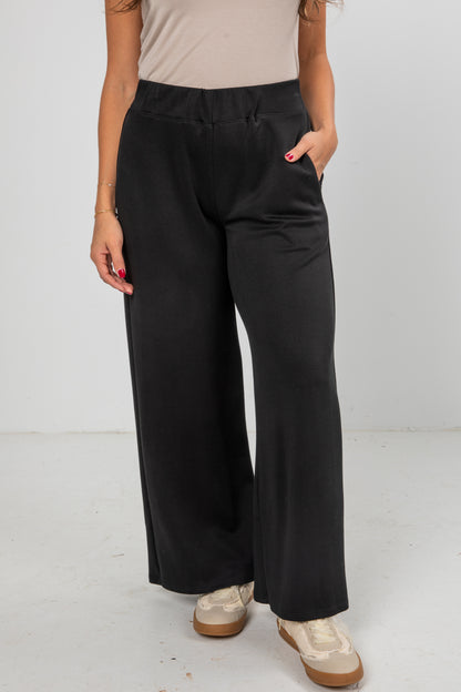 Person wearing black wide-leg pants on a white background