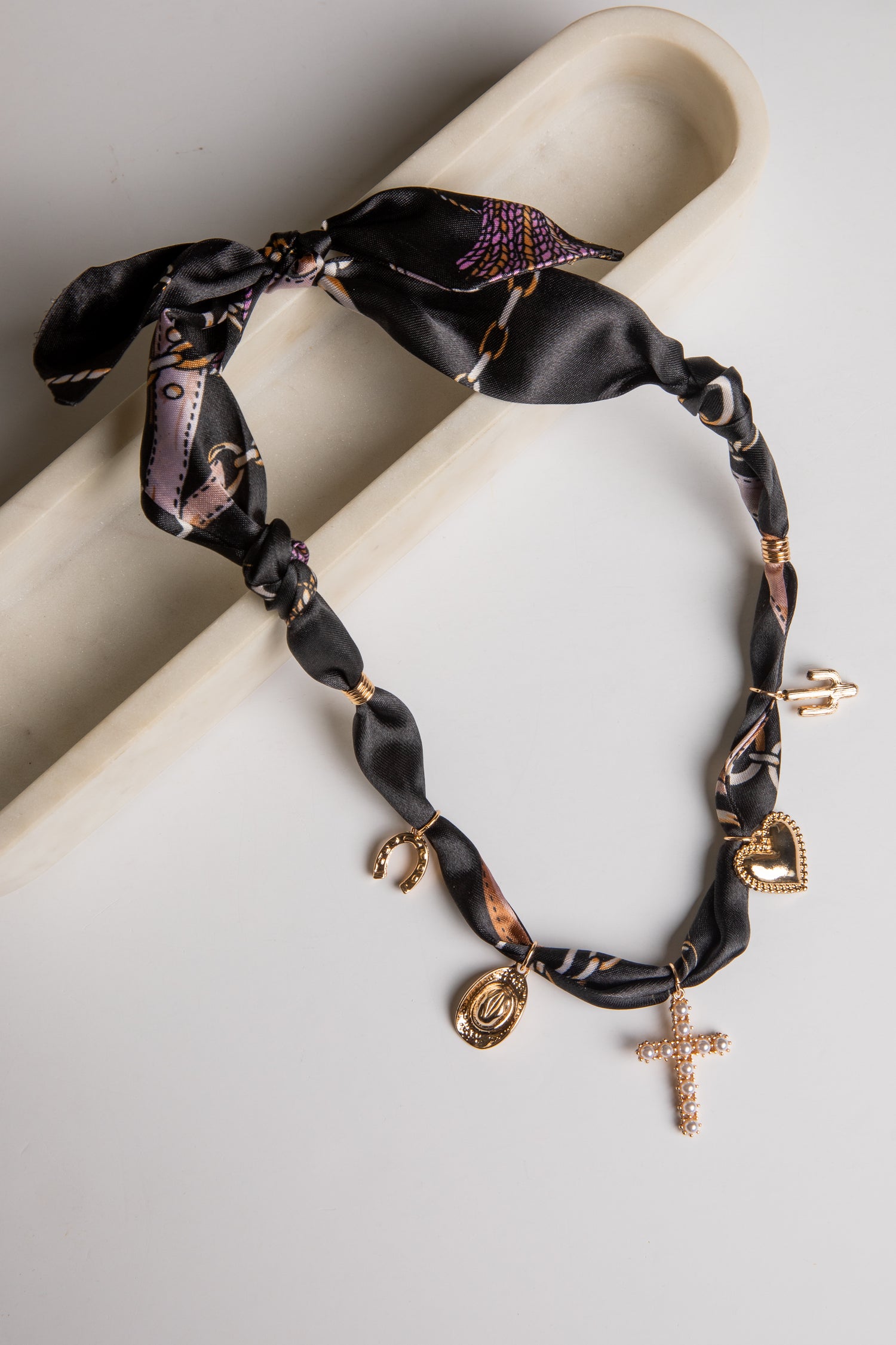 Black satin ribbon bracelet with gold charms on a white surface