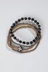 Stack of black beaded bracelets with gold and silver accents on a light gray background