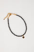 Black beaded anklet with gold chain on a white background