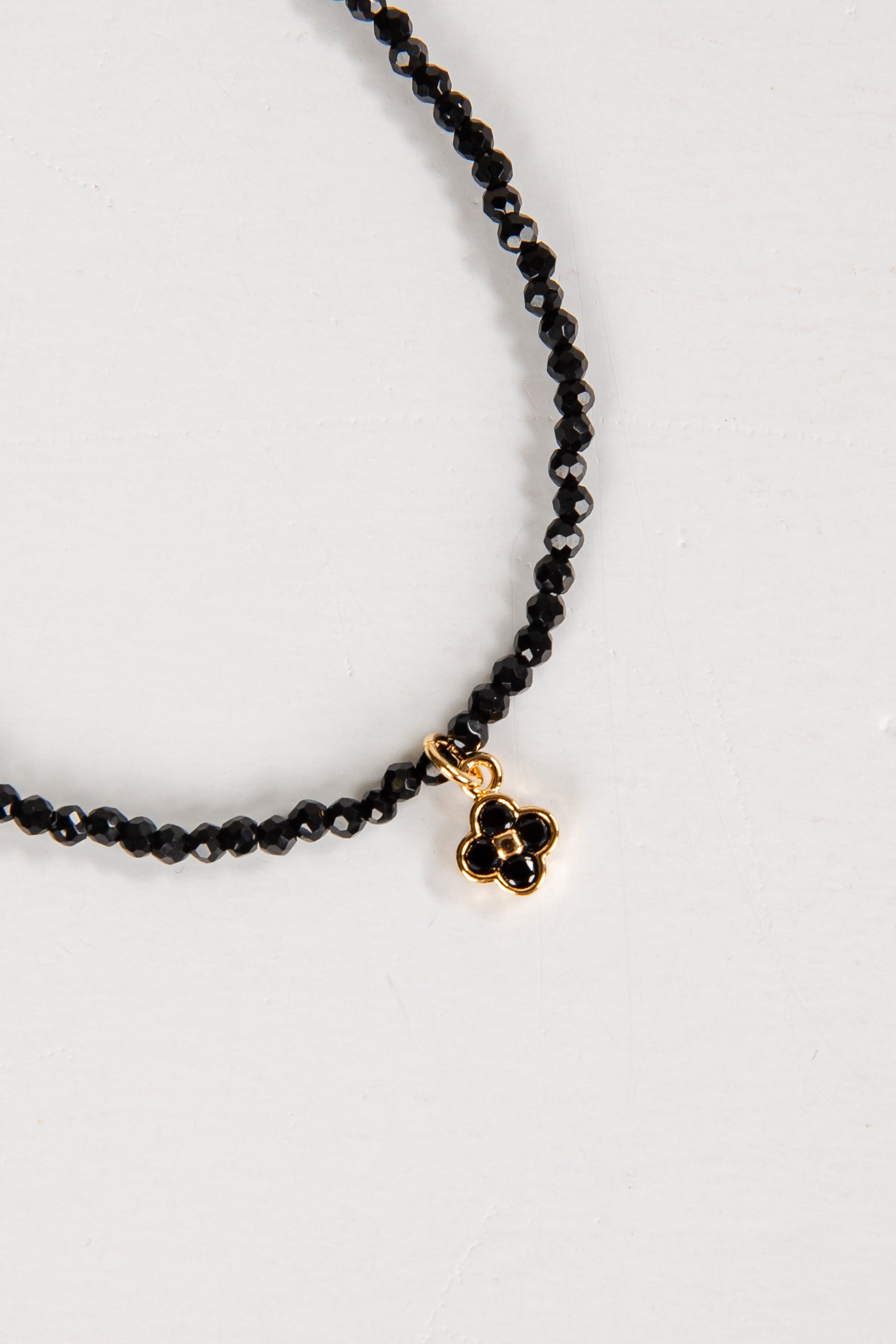 Black beaded necklace with a gold clasp on a white background