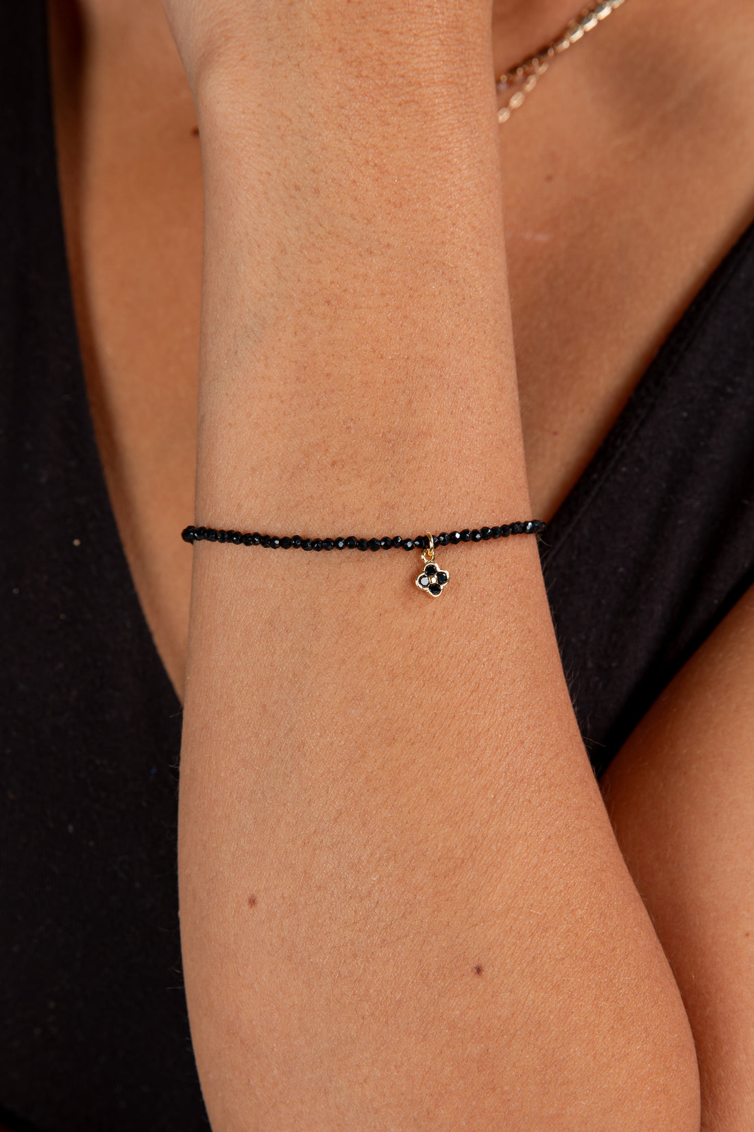 Black beaded bracelet on a wrist with a blurred background