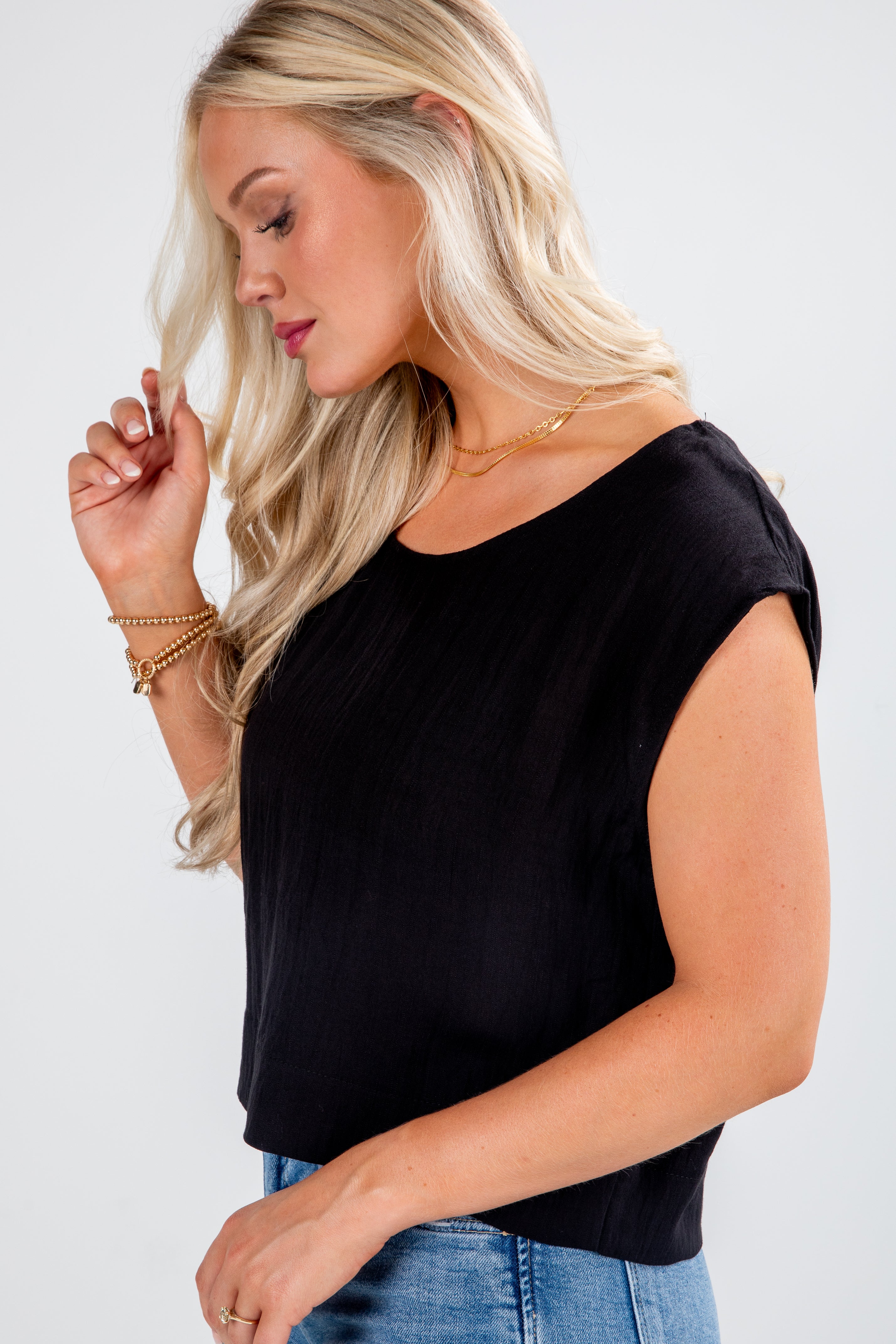 Woman wearing a black sleeveless top and blue jeans on a white background