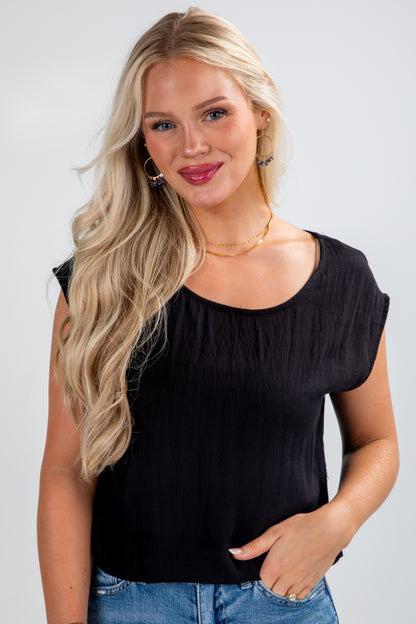 Woman wearing a black sleeveless top and blue jeans on a white background