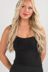 Woman wearing a black tank top against a plain background