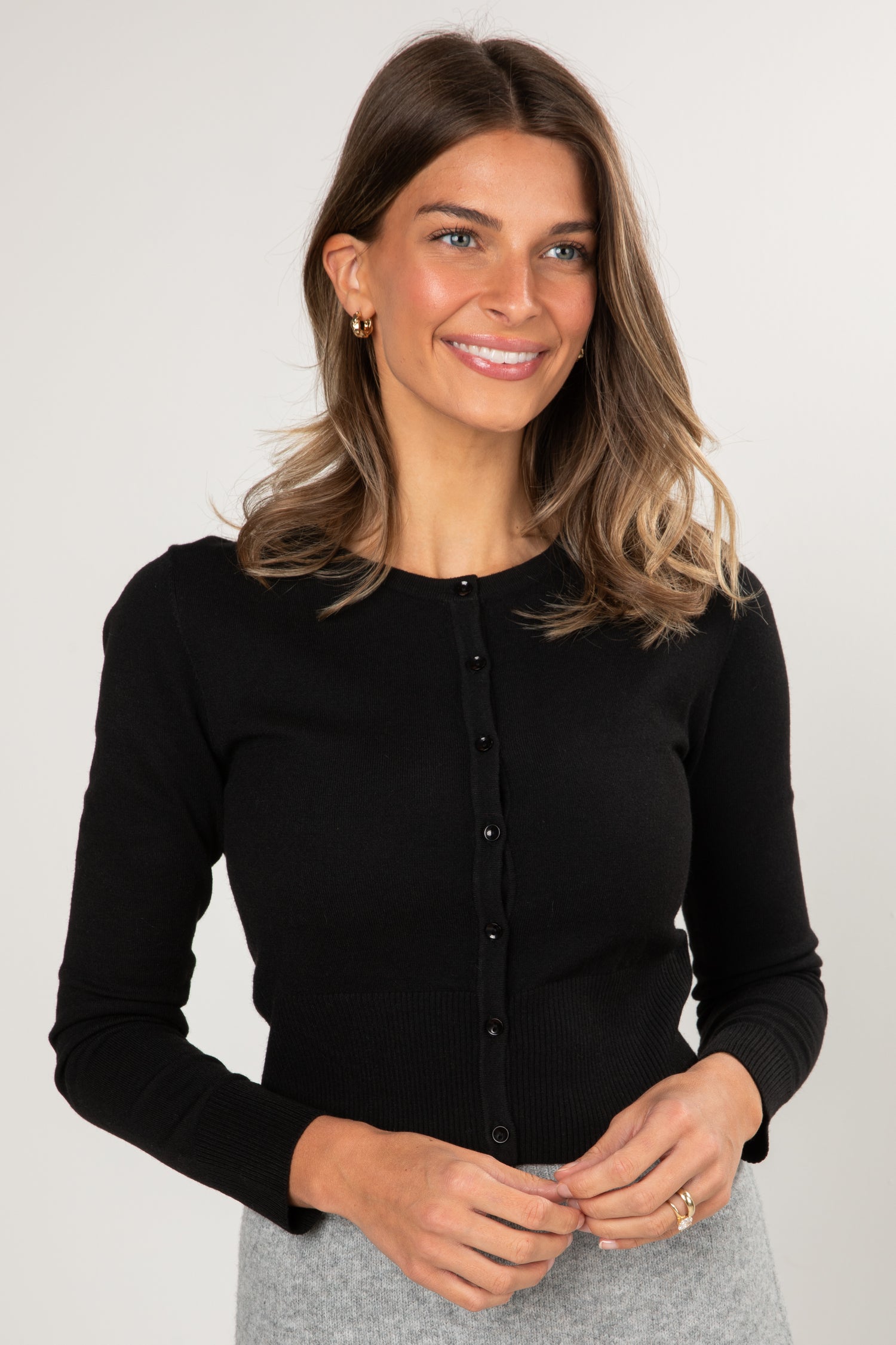 Woman wearing a black long-sleeve top against a plain background
