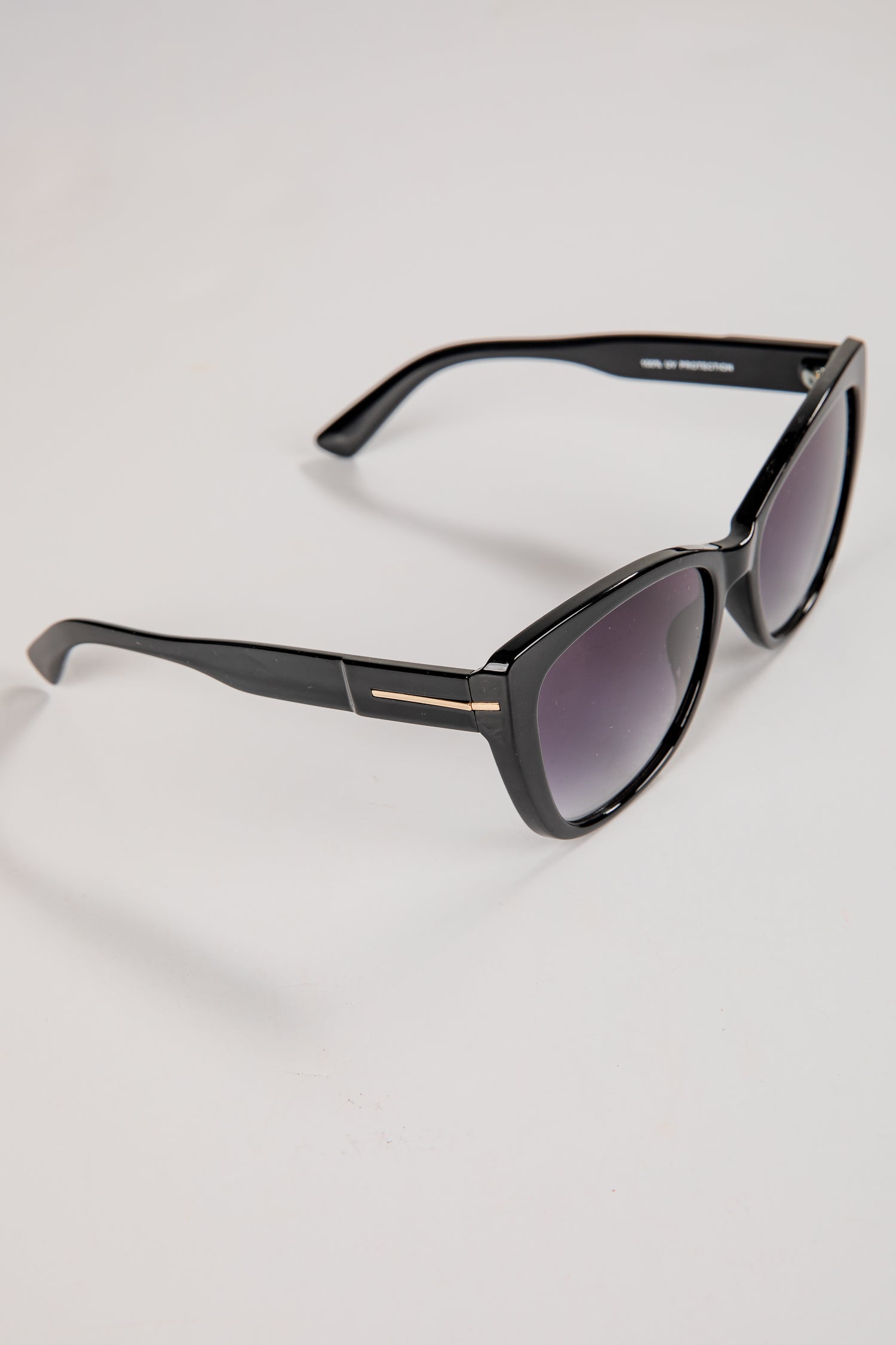 Black sunglasses with a gold accent on a white background