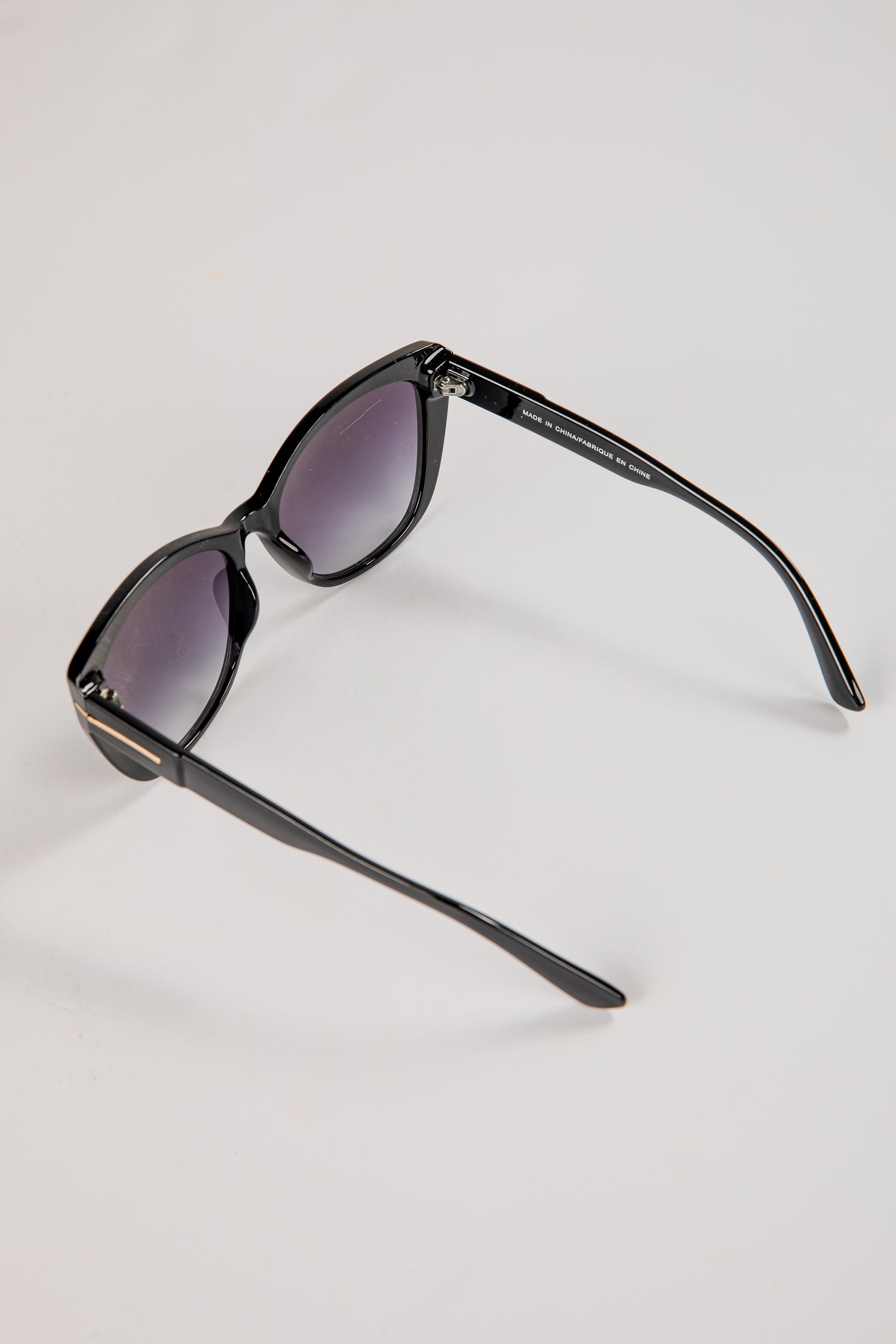 Black sunglasses with purple lenses on a light gray background
