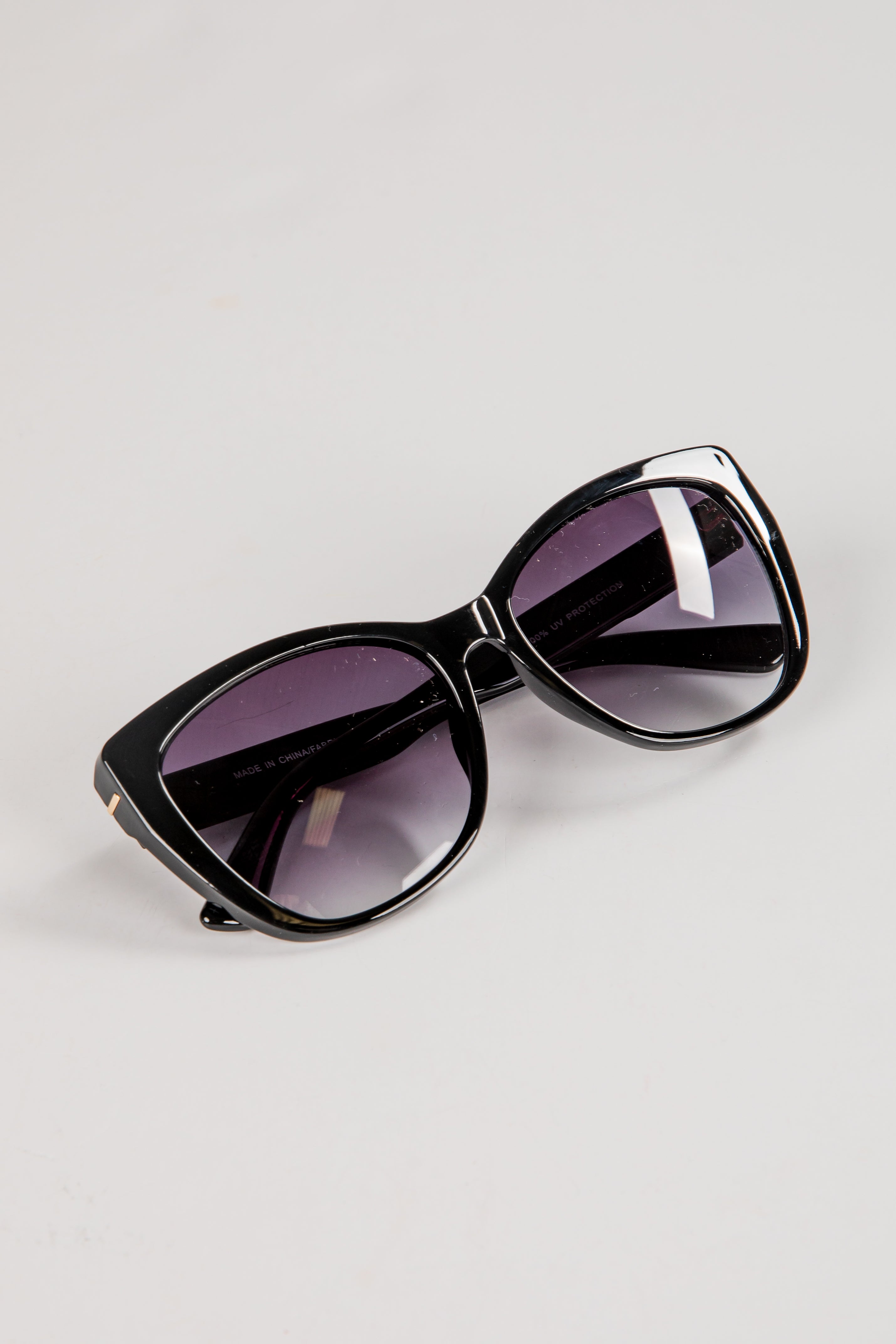 Black sunglasses with purple lenses on a light gray background