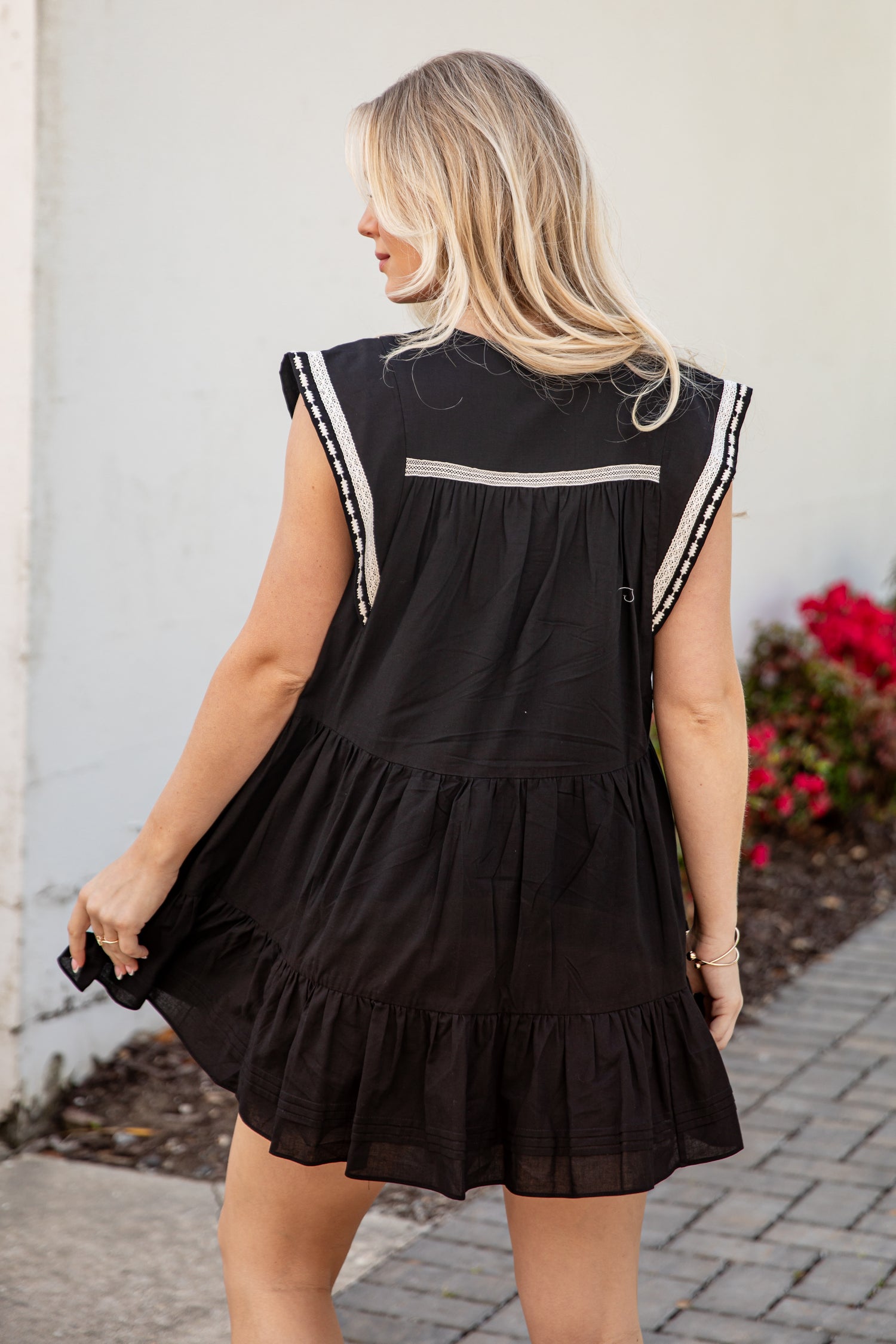 Woman wearing a black dress with white trim, standing outdoors.