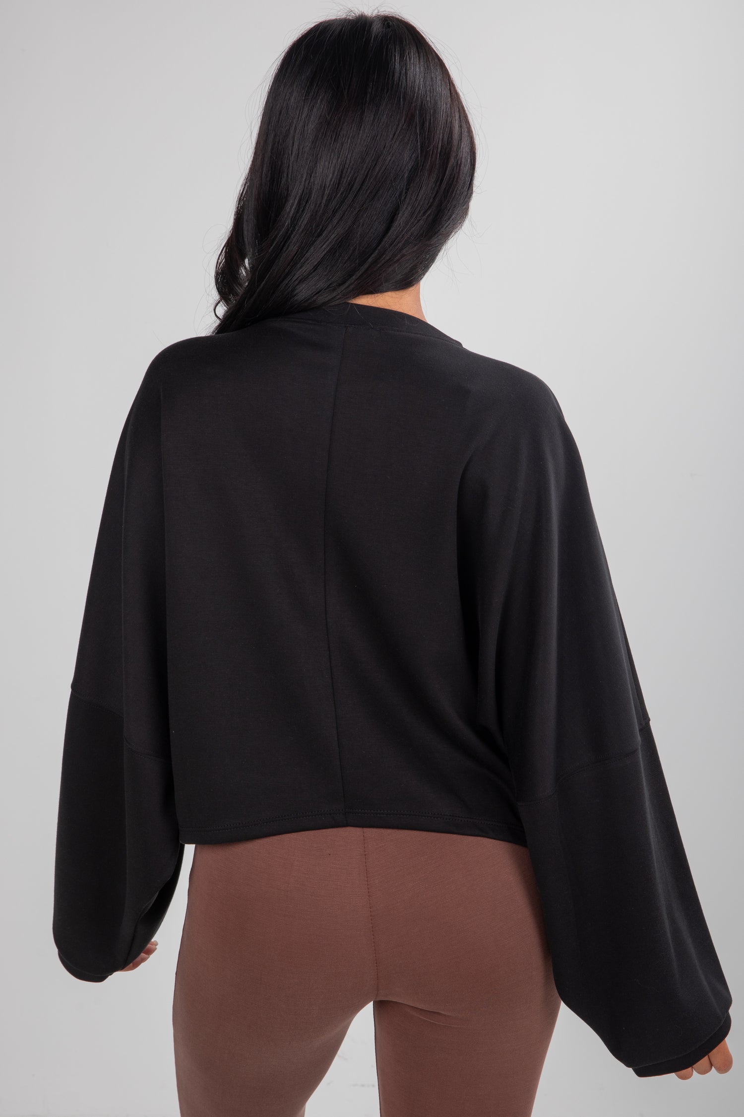 Person wearing a black top and brown pants on a plain background