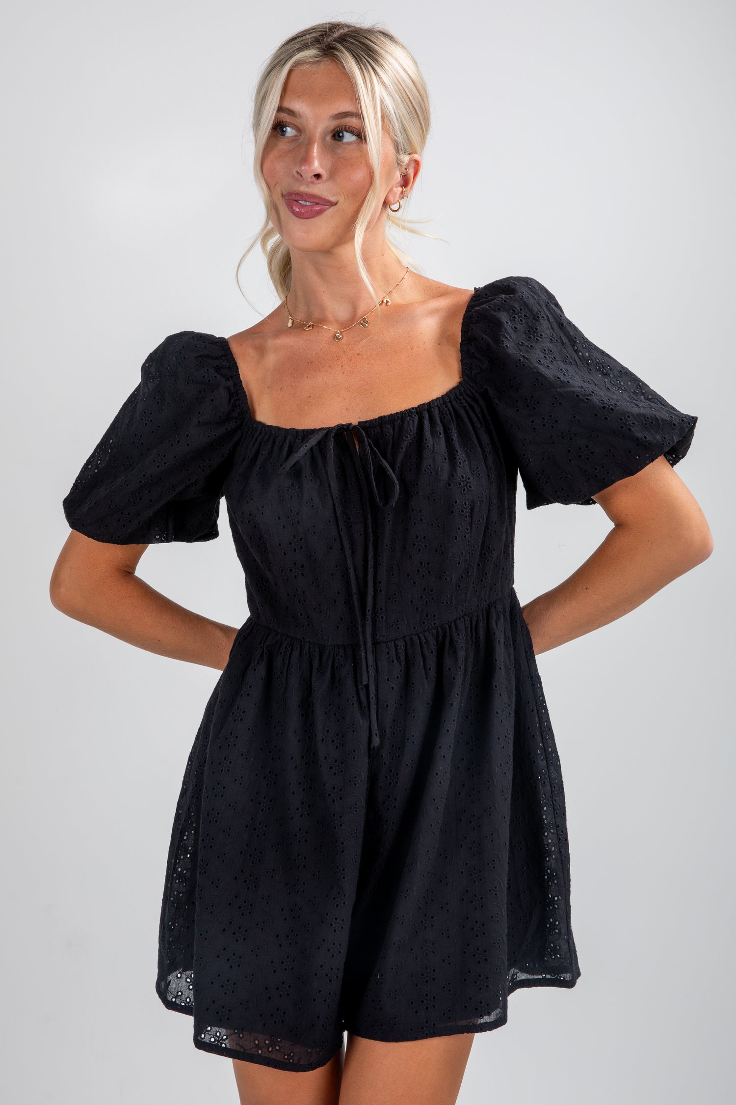 Woman wearing a black dress with puffed sleeves on a plain background