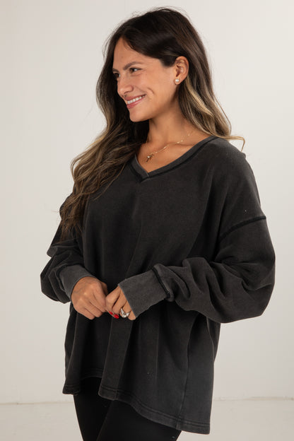 Woman wearing a black oversized sweater against a white background