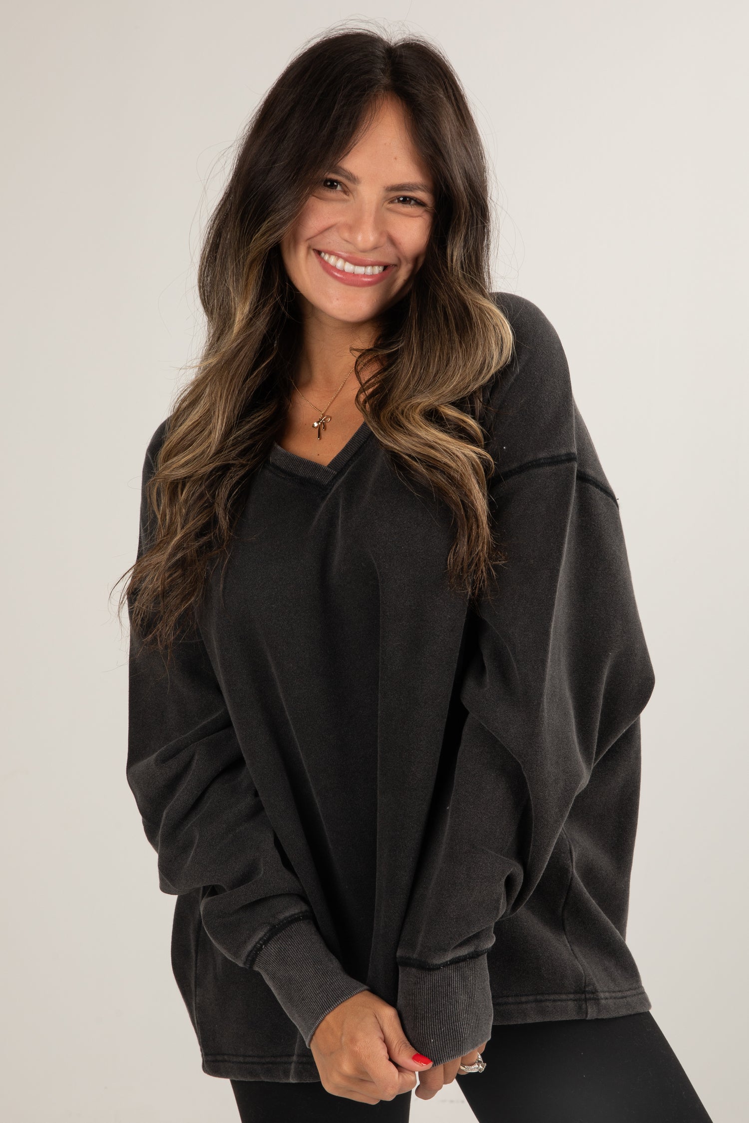 Woman wearing a black oversized sweatshirt against a plain background