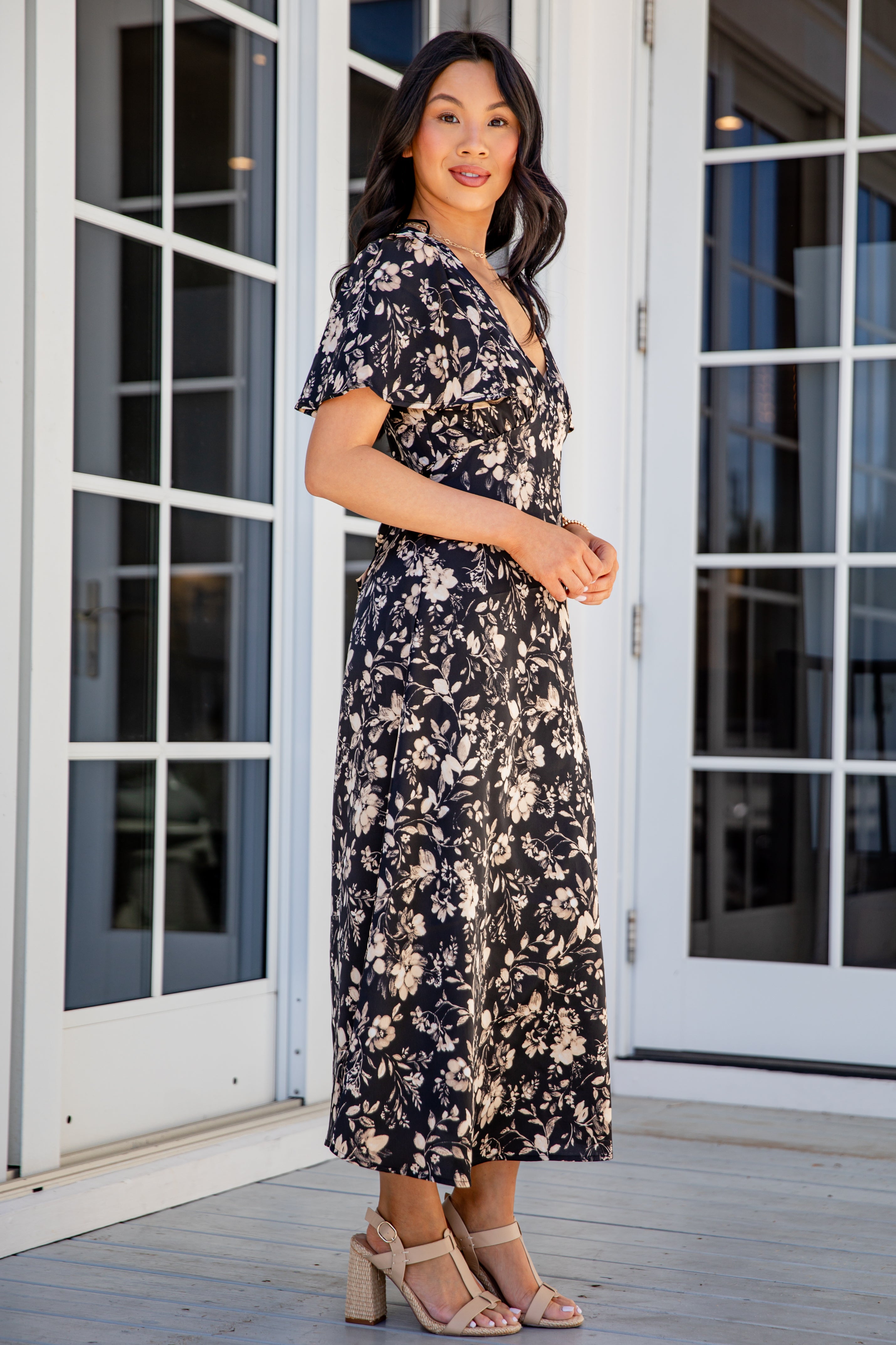 Woman wearing a floral dress standing in front of glass doors.