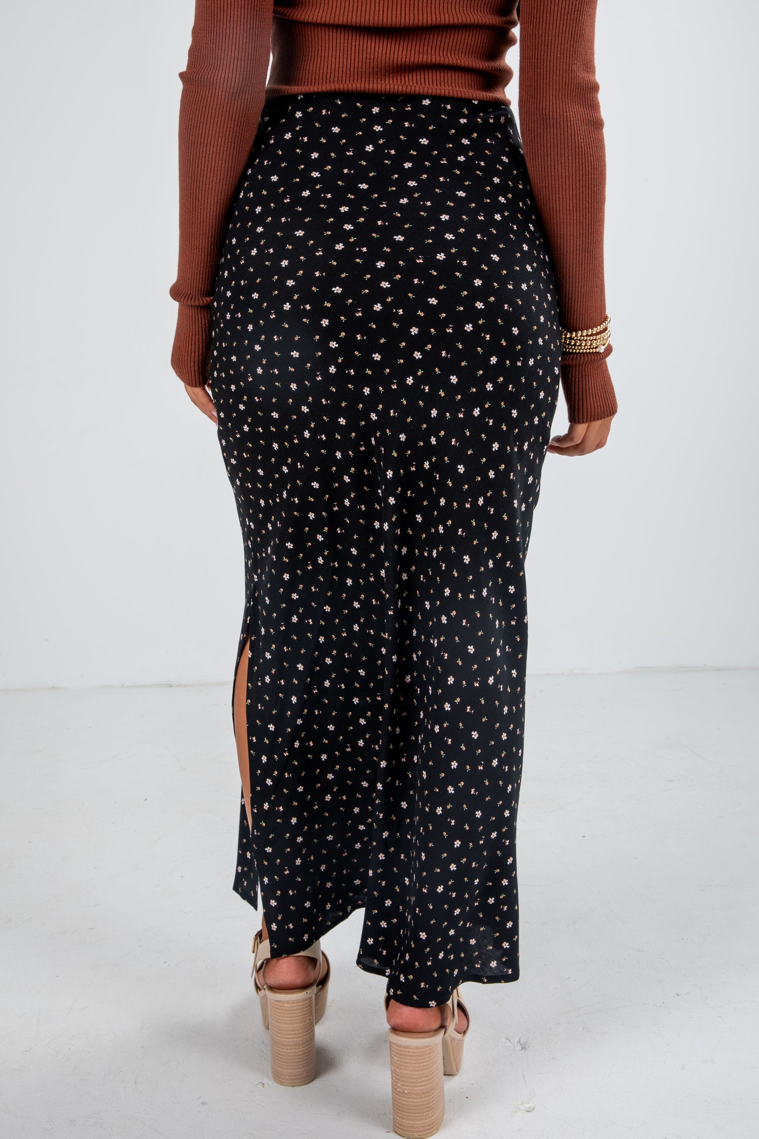 Person wearing a black patterned skirt with a white background