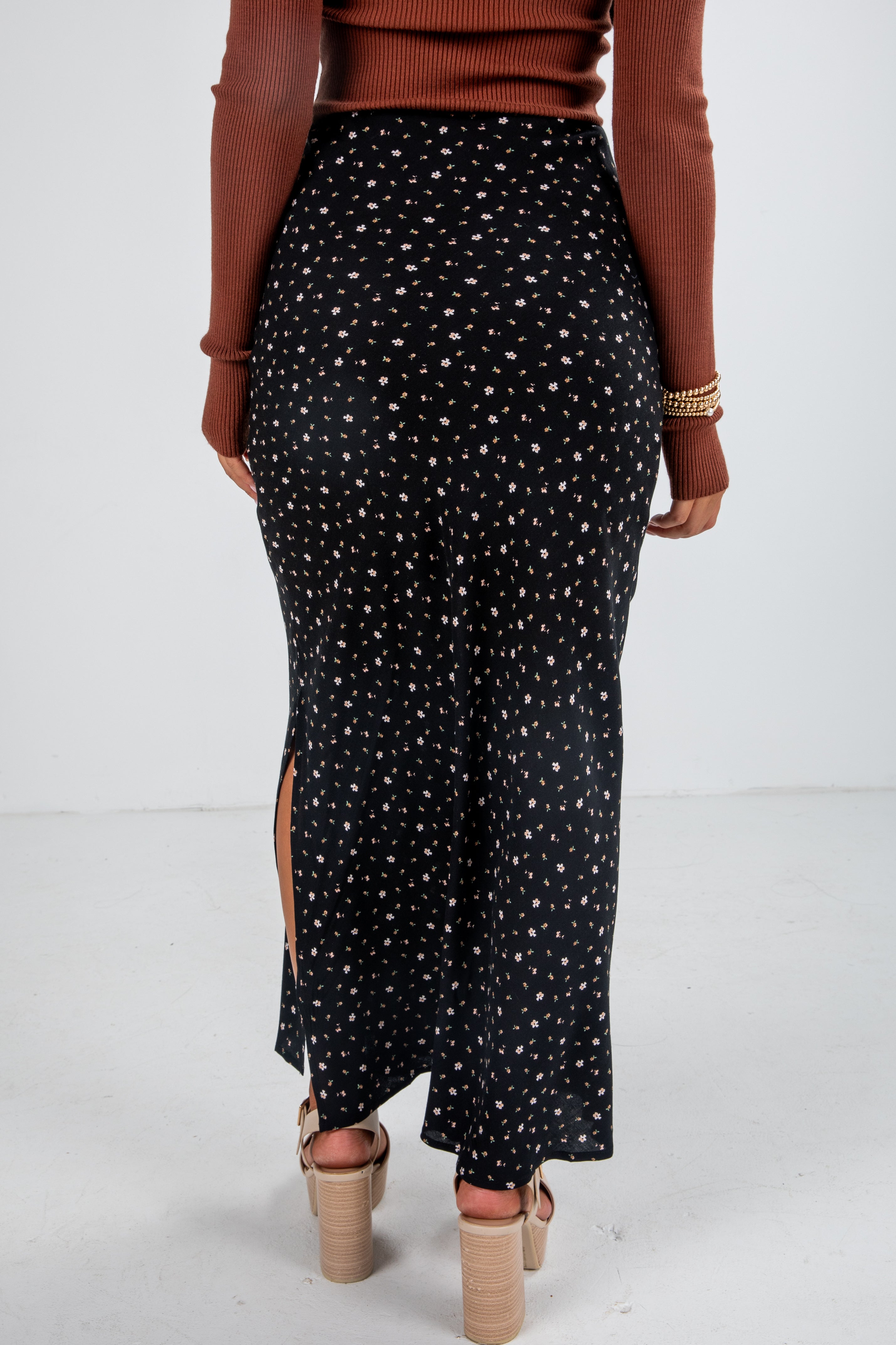 Person wearing a black patterned skirt with a white background