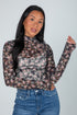 Woman wearing a floral long-sleeve top and jeans against a plain background