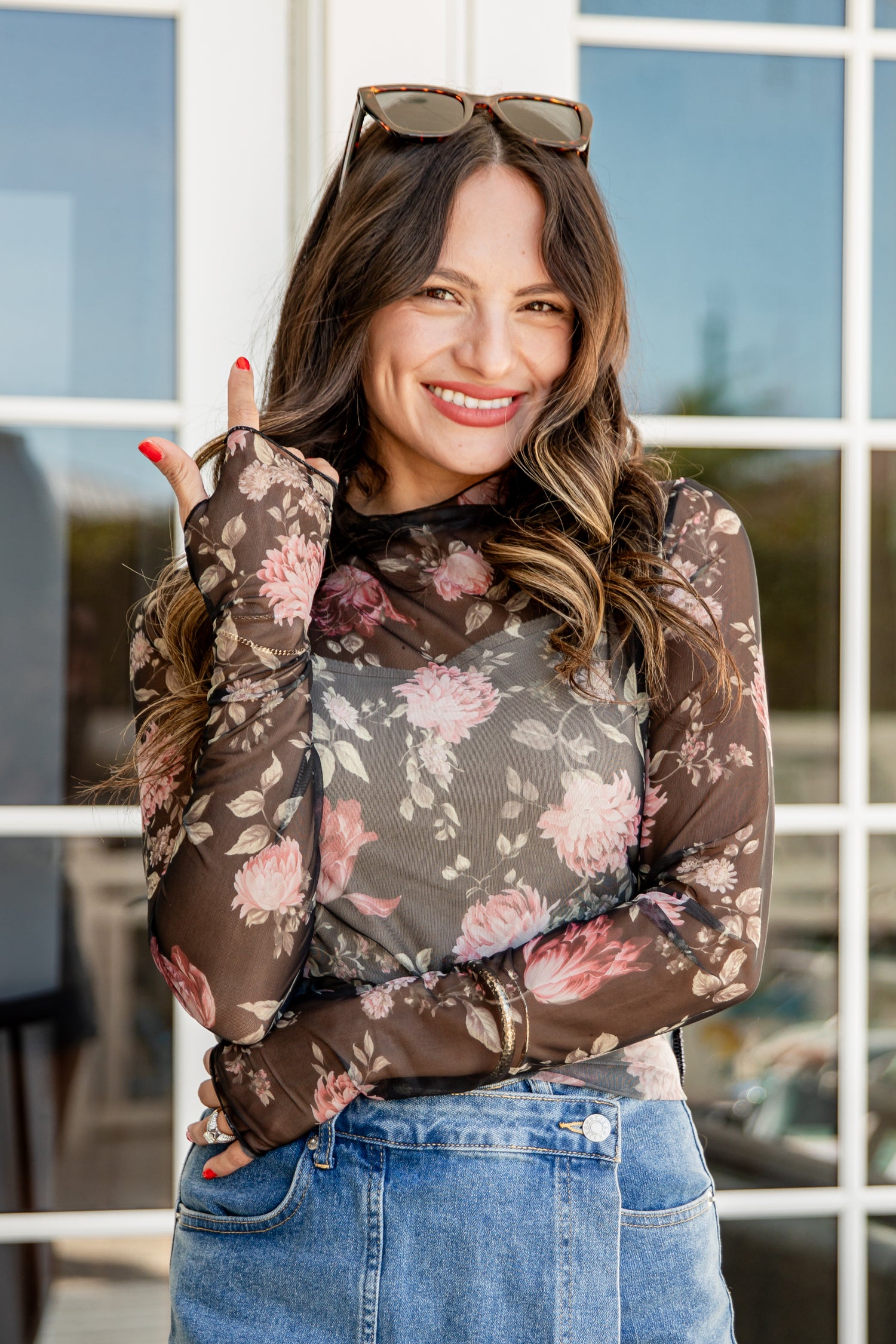 Woman wearing a floral long-sleeve top and jeans outdoors.