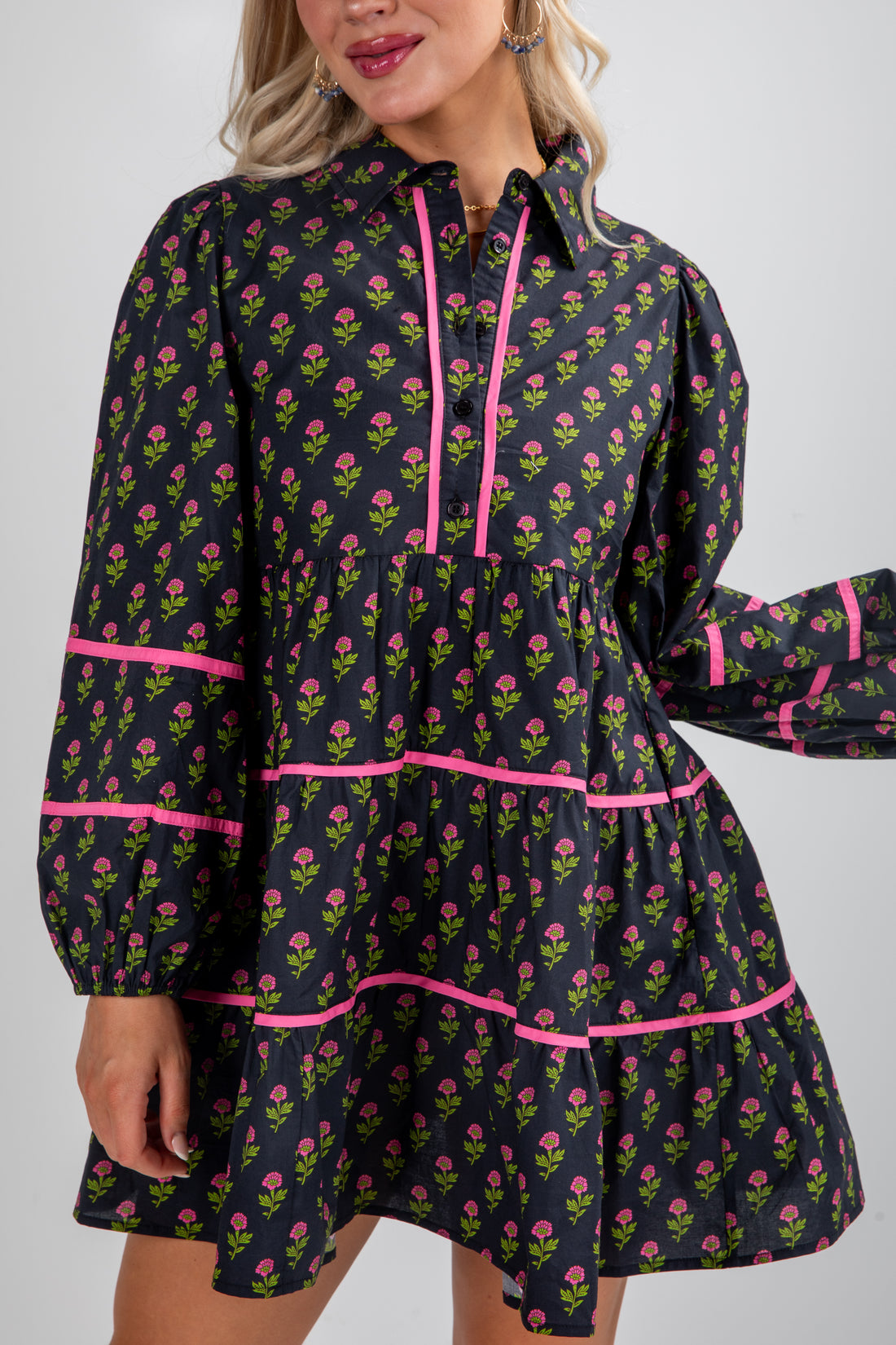 Woman wearing a floral dress with pink accents on a plain background