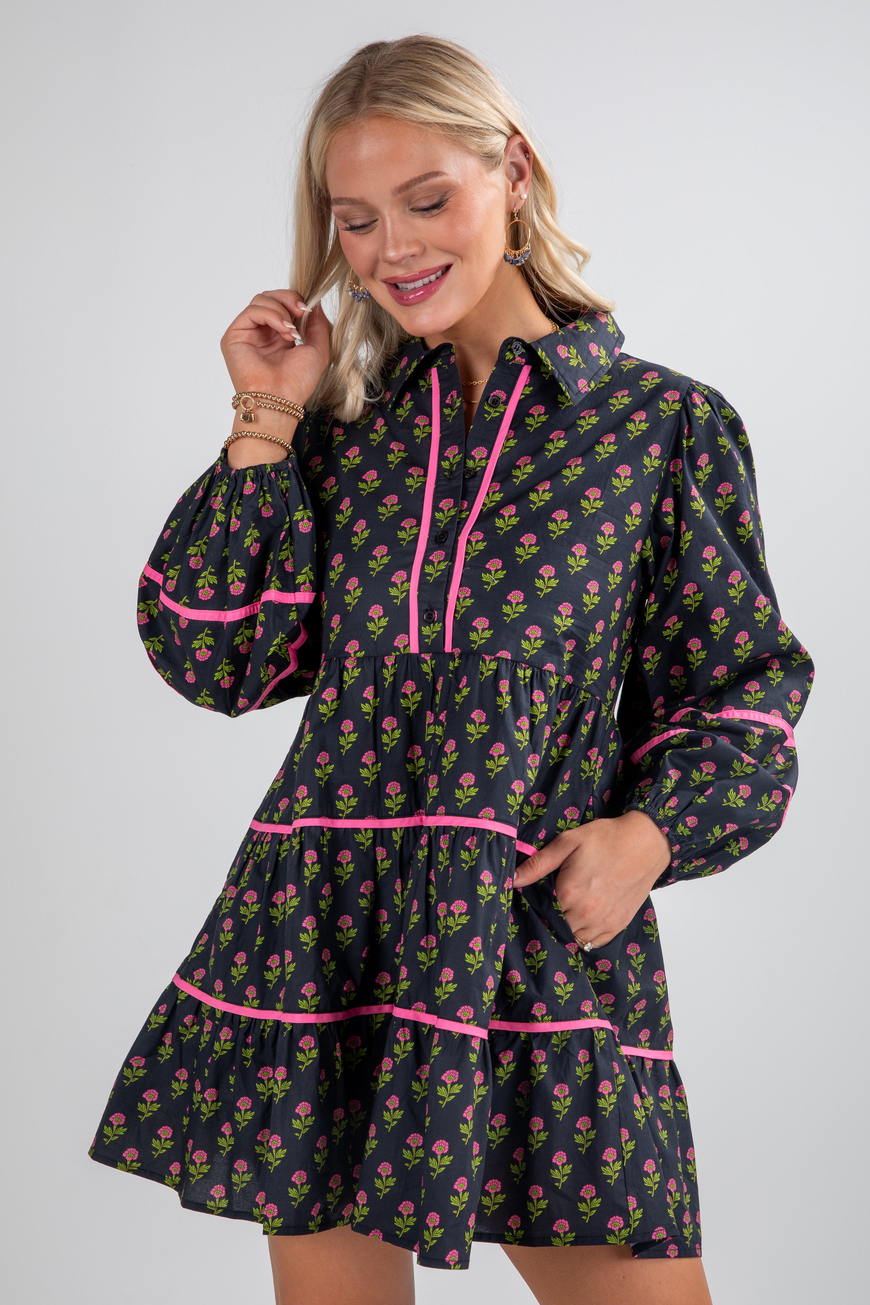 Woman wearing a floral dress with pink accents on a plain background