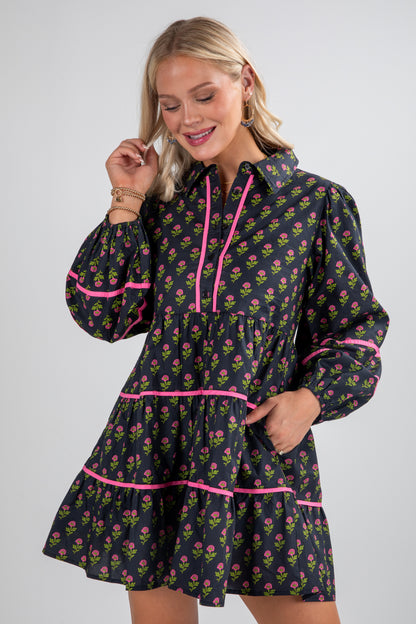 Woman wearing a floral dress with pink accents on a plain background