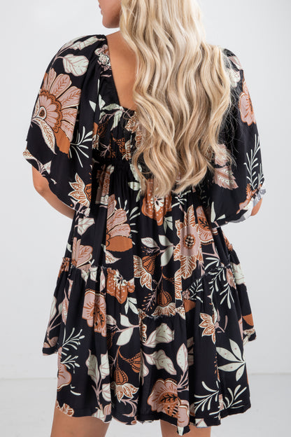 Woman wearing a black floral dress with a white background