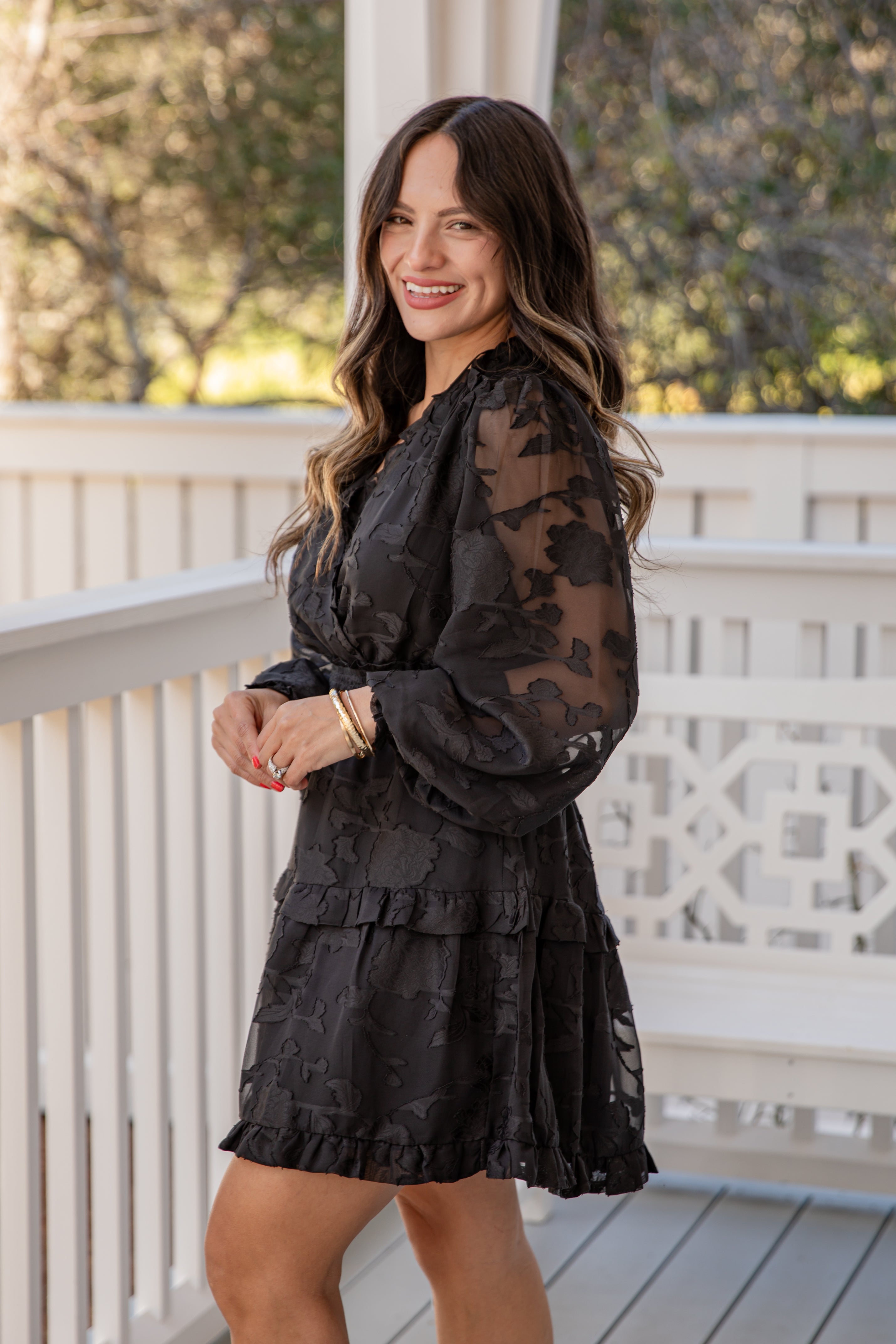 Woman wearing a black floral dress on a balcony