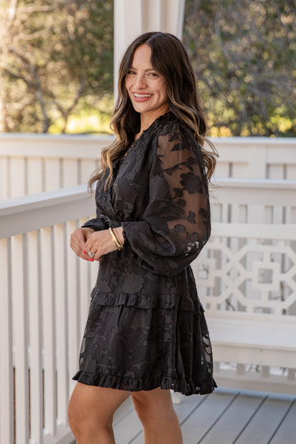 Woman wearing a black floral dress on a balcony