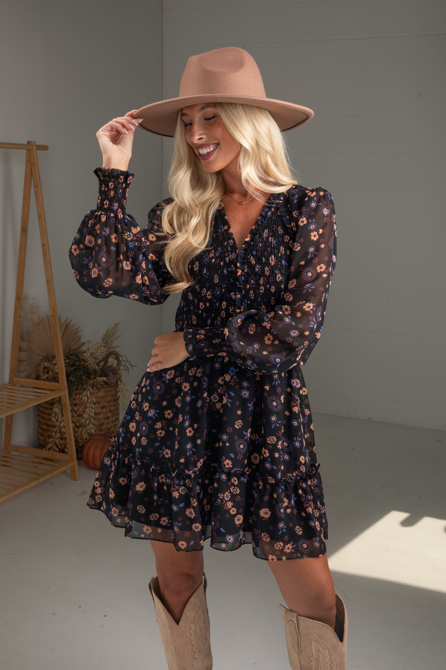 Woman wearing a floral dress and brown hat indoors