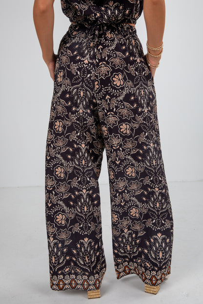Person wearing a dark floral jumpsuit on a light gray background