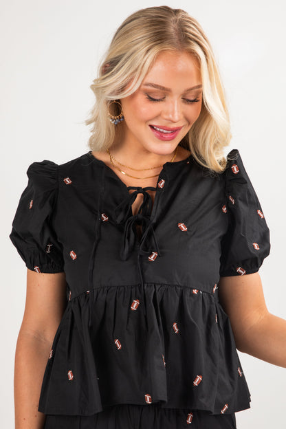 Woman wearing a black blouse with small pink details on a white background