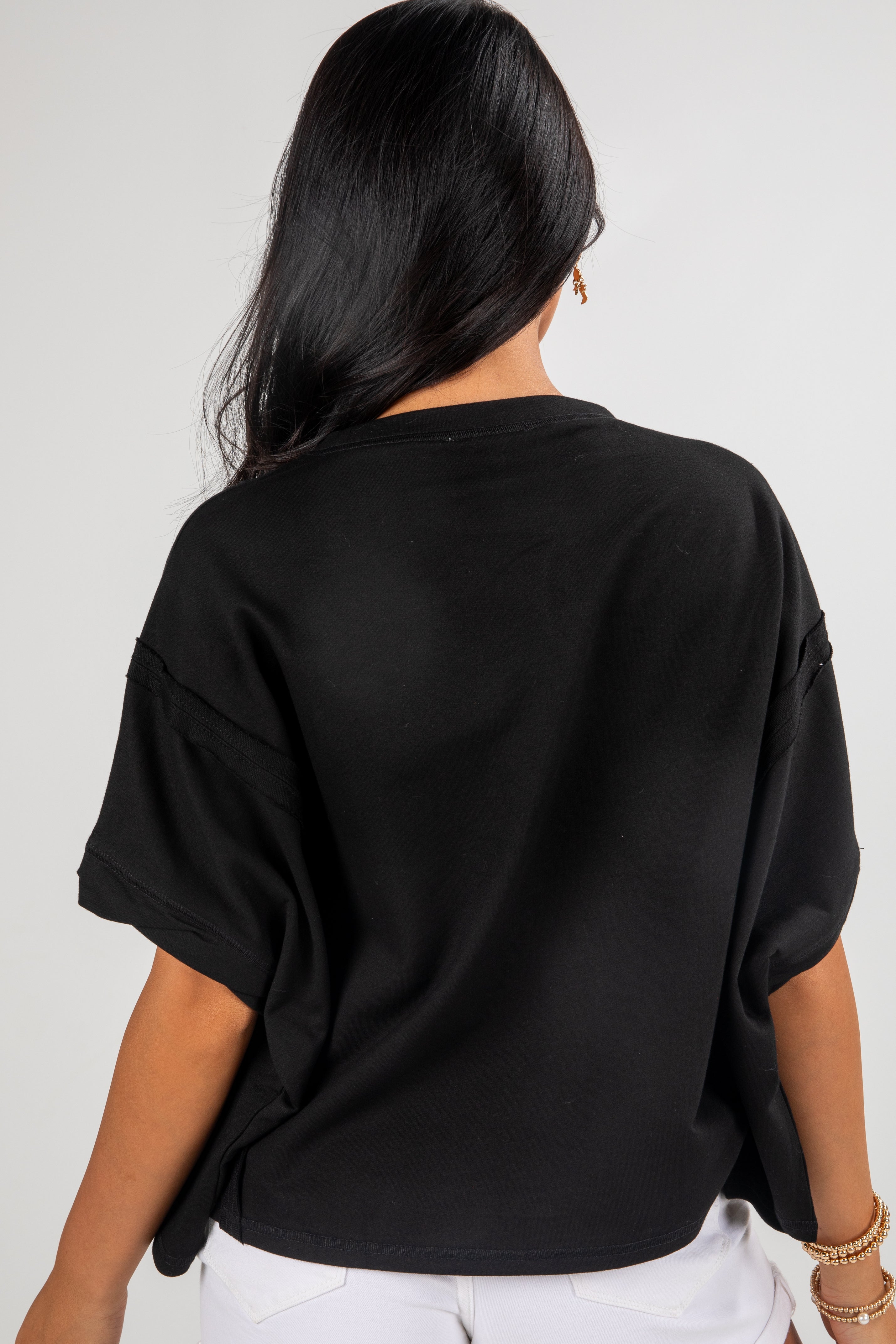 Person wearing a black oversized t-shirt against a plain background