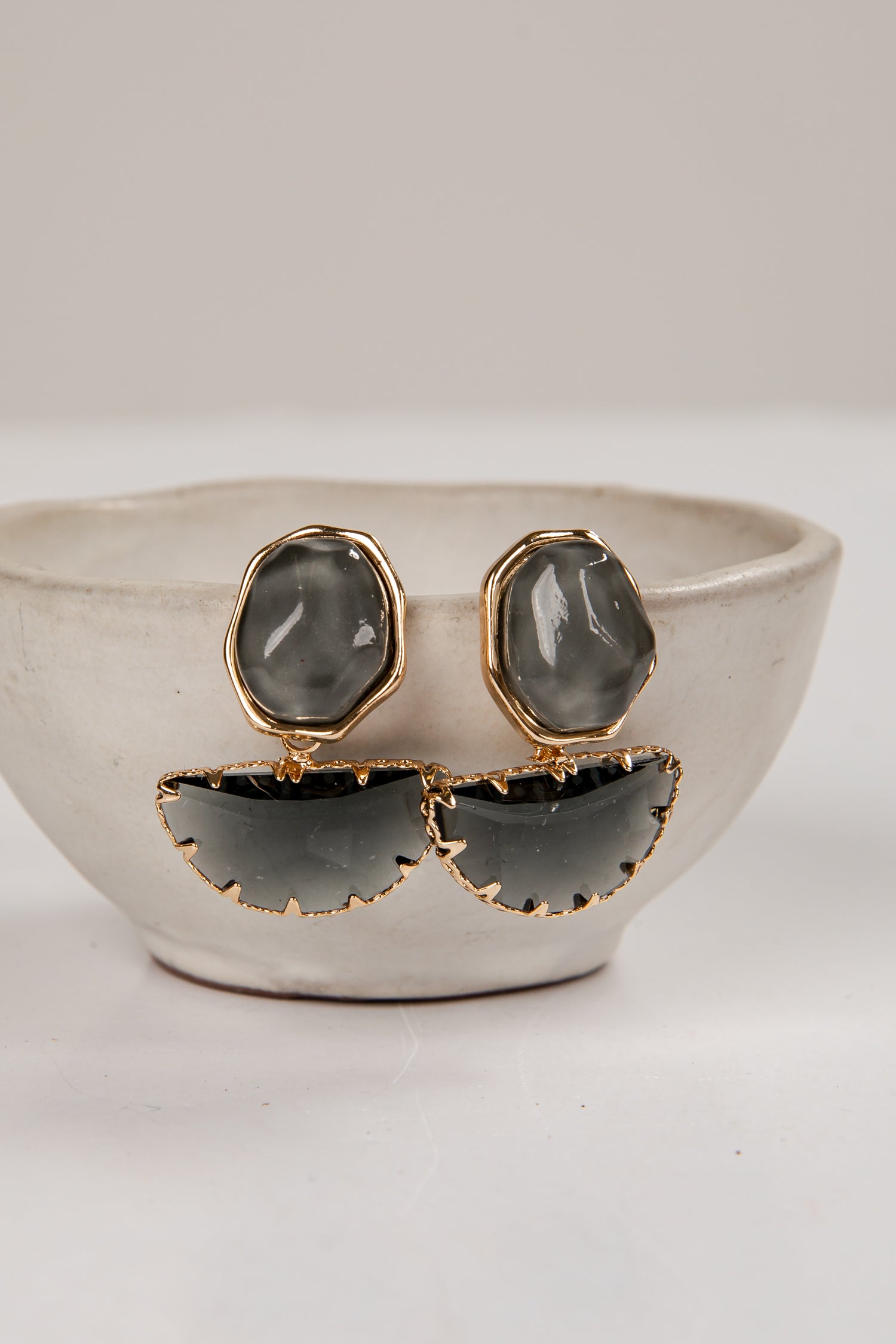 Pair of earrings with gold and gray design on a white surface