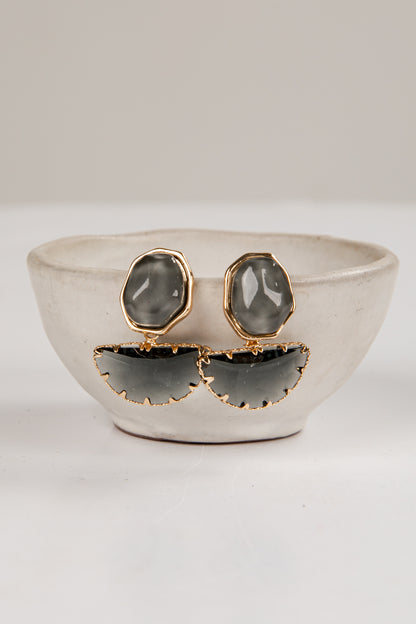Pair of earrings with gray stones and gold accents on a white surface.