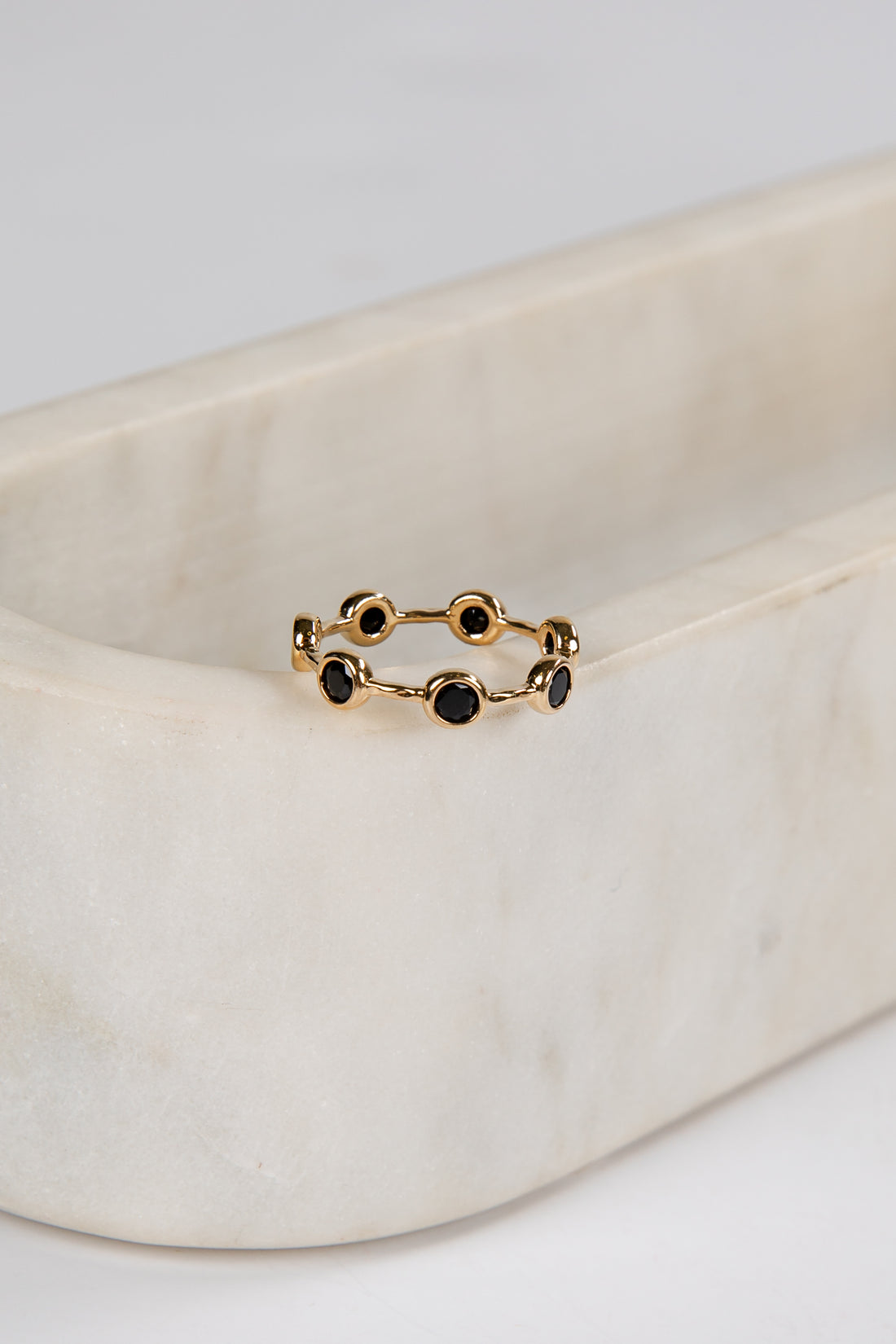 Gold ring with black stones on a beige fabric background