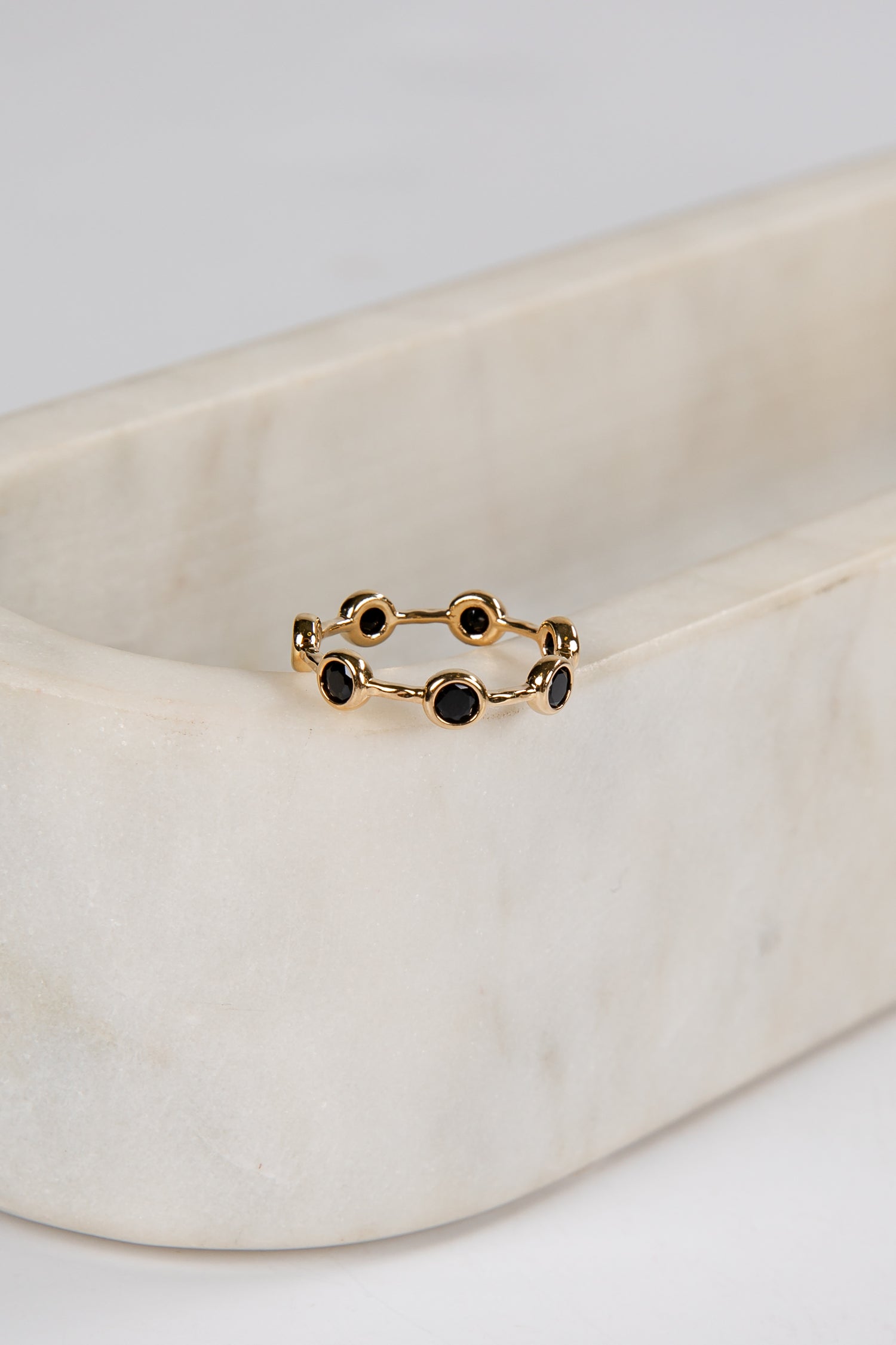 Gold ring with black stones on a beige fabric background